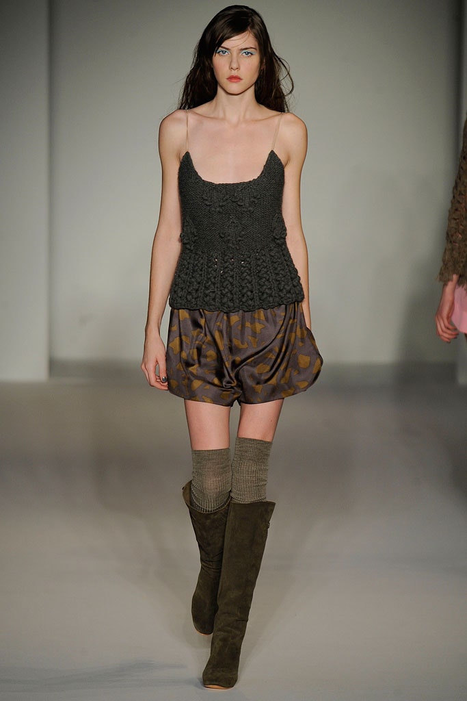 A relaxed brown knit sleeveless top paired with high-waisted pleated shorts.