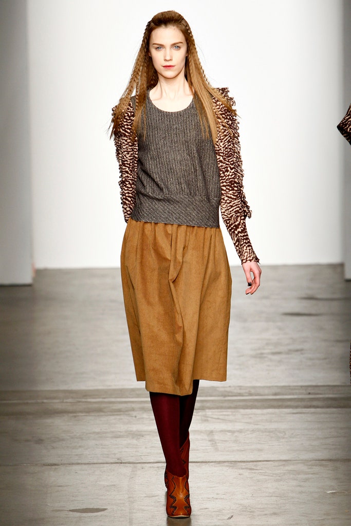 A relaxed gray long-sleeve top paired with a pleated brown skirt.