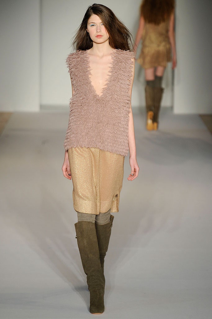A fitted pink wool sleeveless top with a V-neckline and layered asymmetric design paired with a beige skirt.