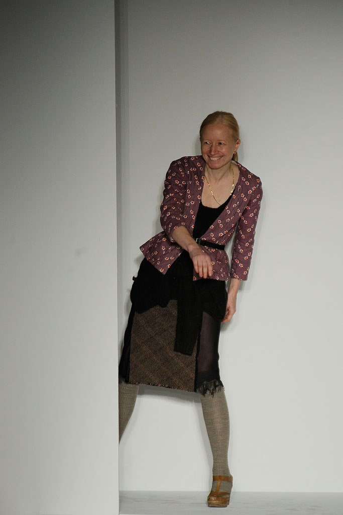 A fitted purple printed jacket paired with a black asymmetric skirt.
