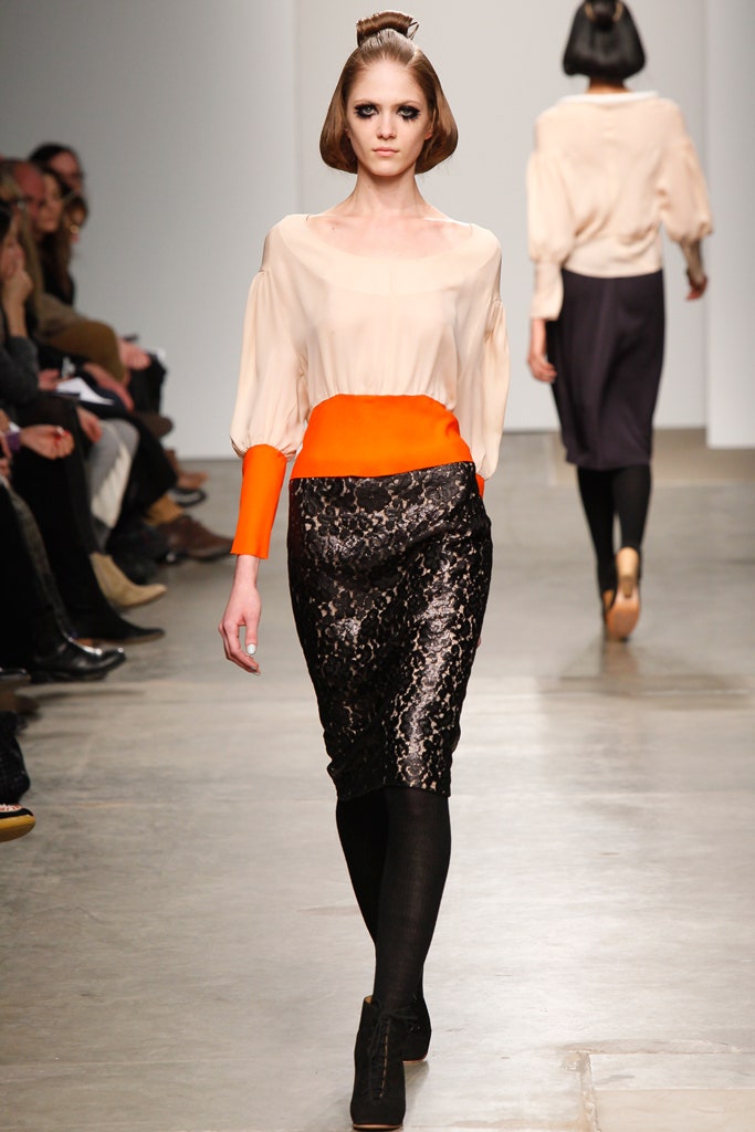 A fitted beige silk blouse with long sleeves paired with a fitted black sequined pencil skirt.