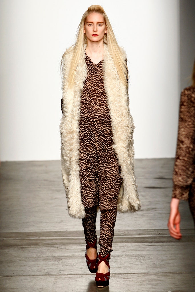 A relaxed brown printed dress paired with a cream fur coat and long sleeves.