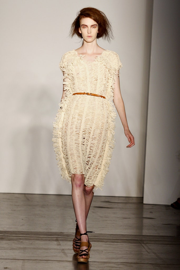 A fitted beige dress with short sleeves, fringed details, and a tiered design.