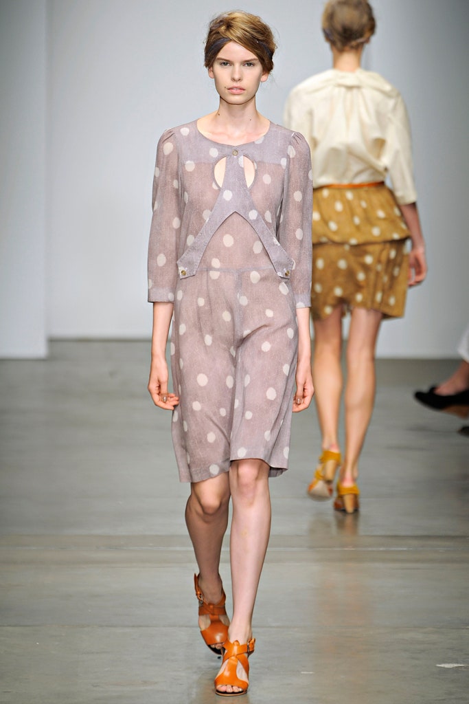 A fitted beige dress with three-quarter sleeves, a V-neckline, and polka-dot pattern.