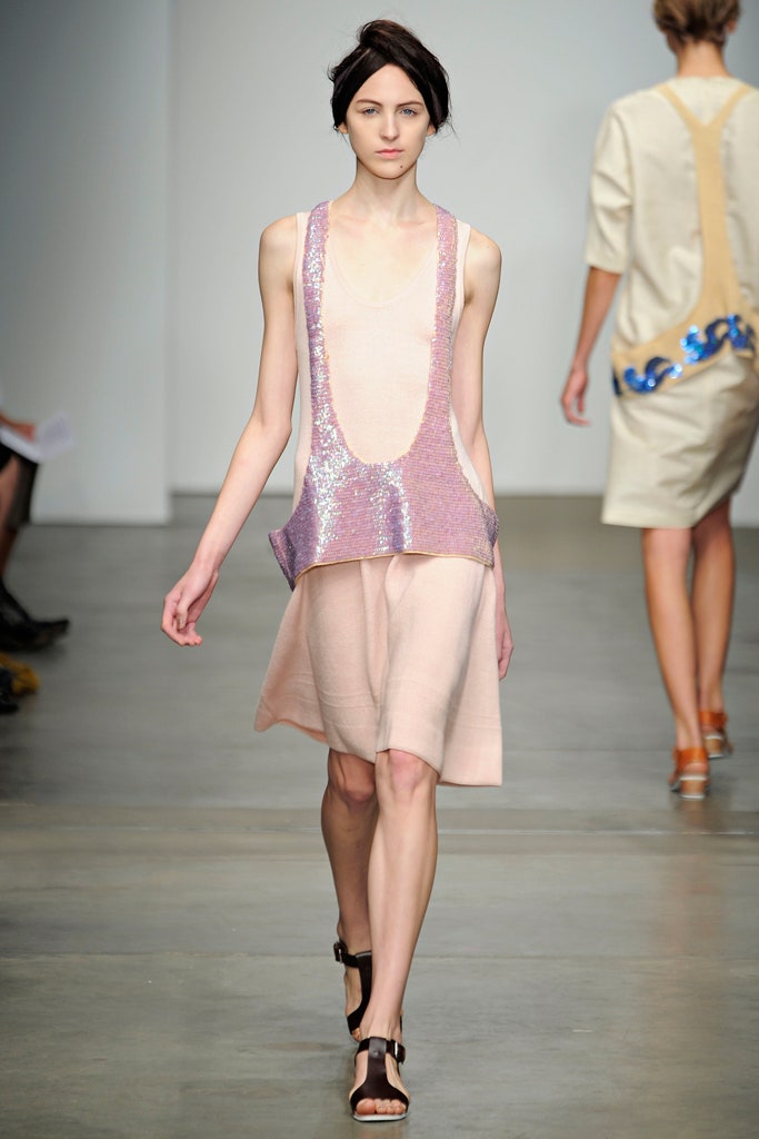 A fitted pink silk sleeveless dress with a V-neckline and asymmetric design.