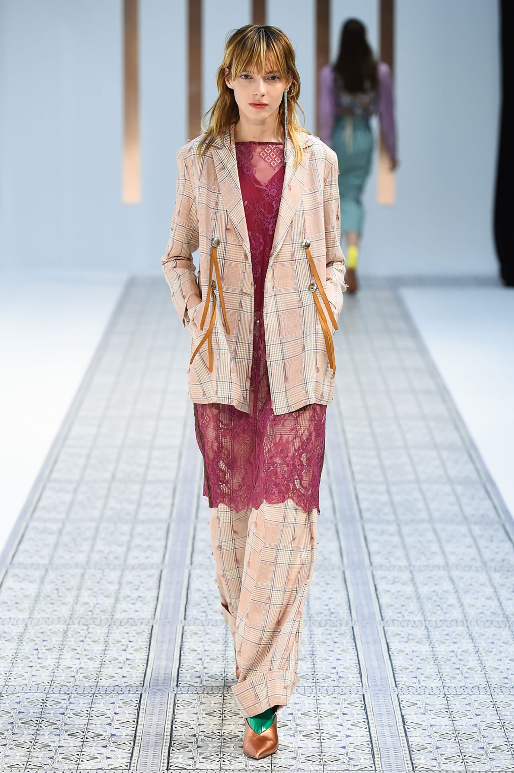 A fitted pink lace dress layered under a collared jacket, featuring an asymmetric design.