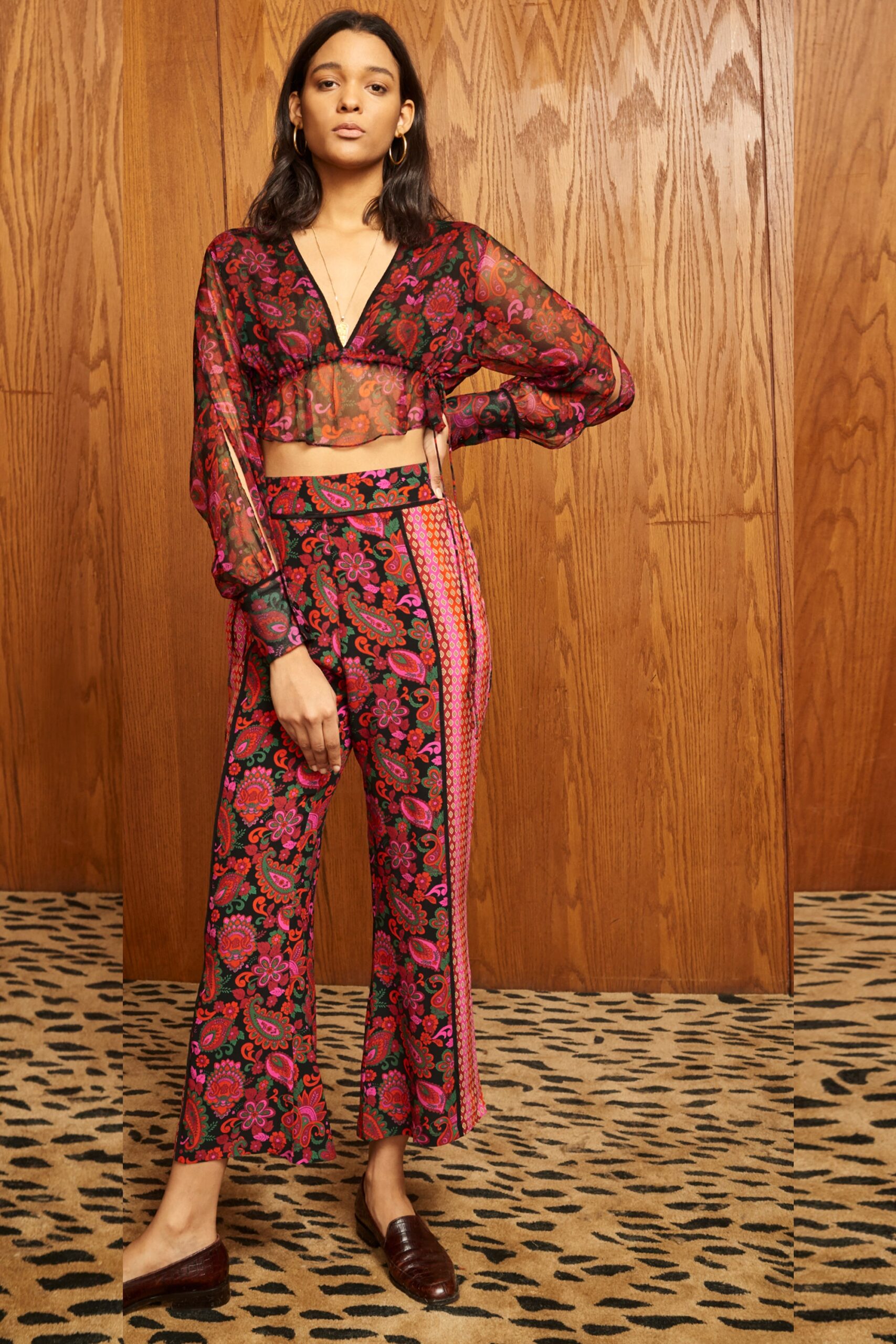 A fitted floral silk top with long sleeves and a V-neck, paired with flared pants.