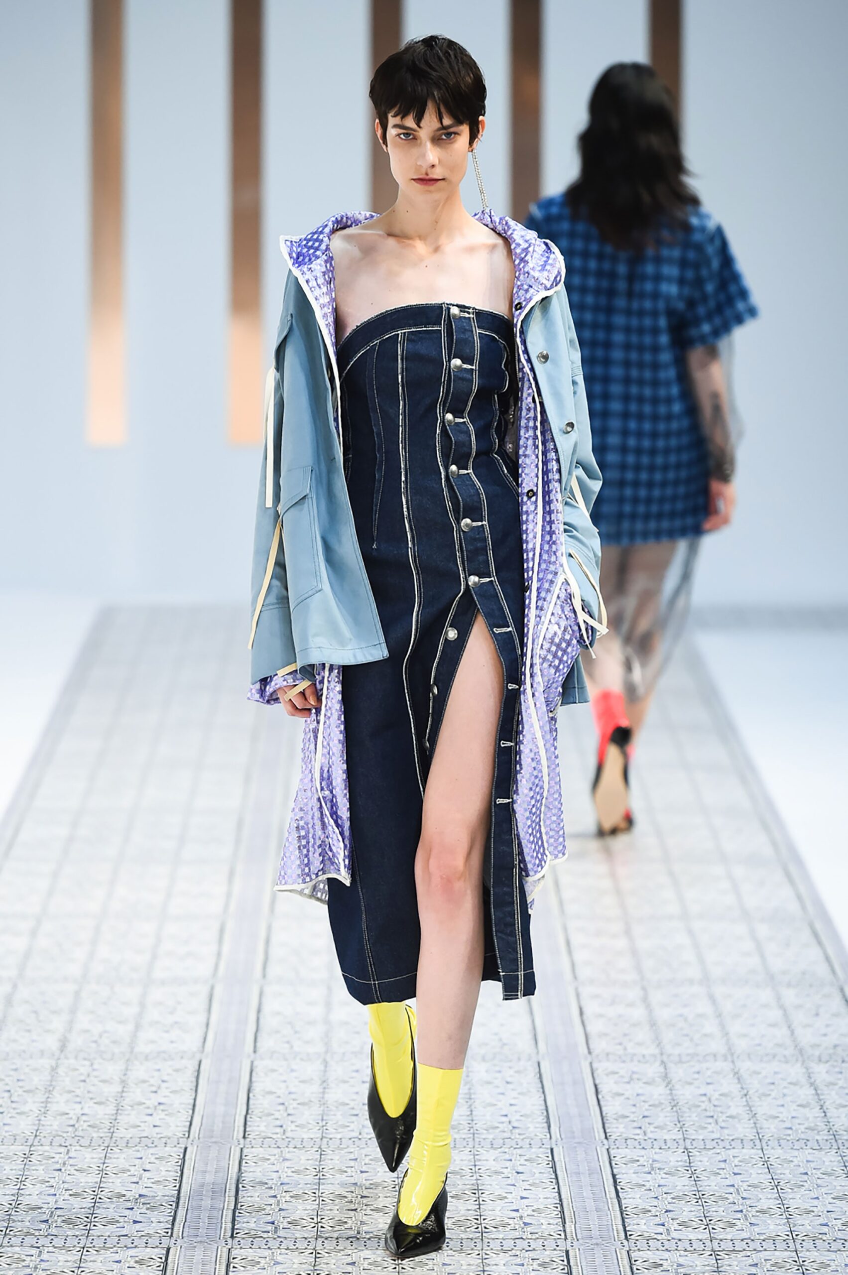 A fitted blue denim dress with a buttoned front and layered jacket detail.
