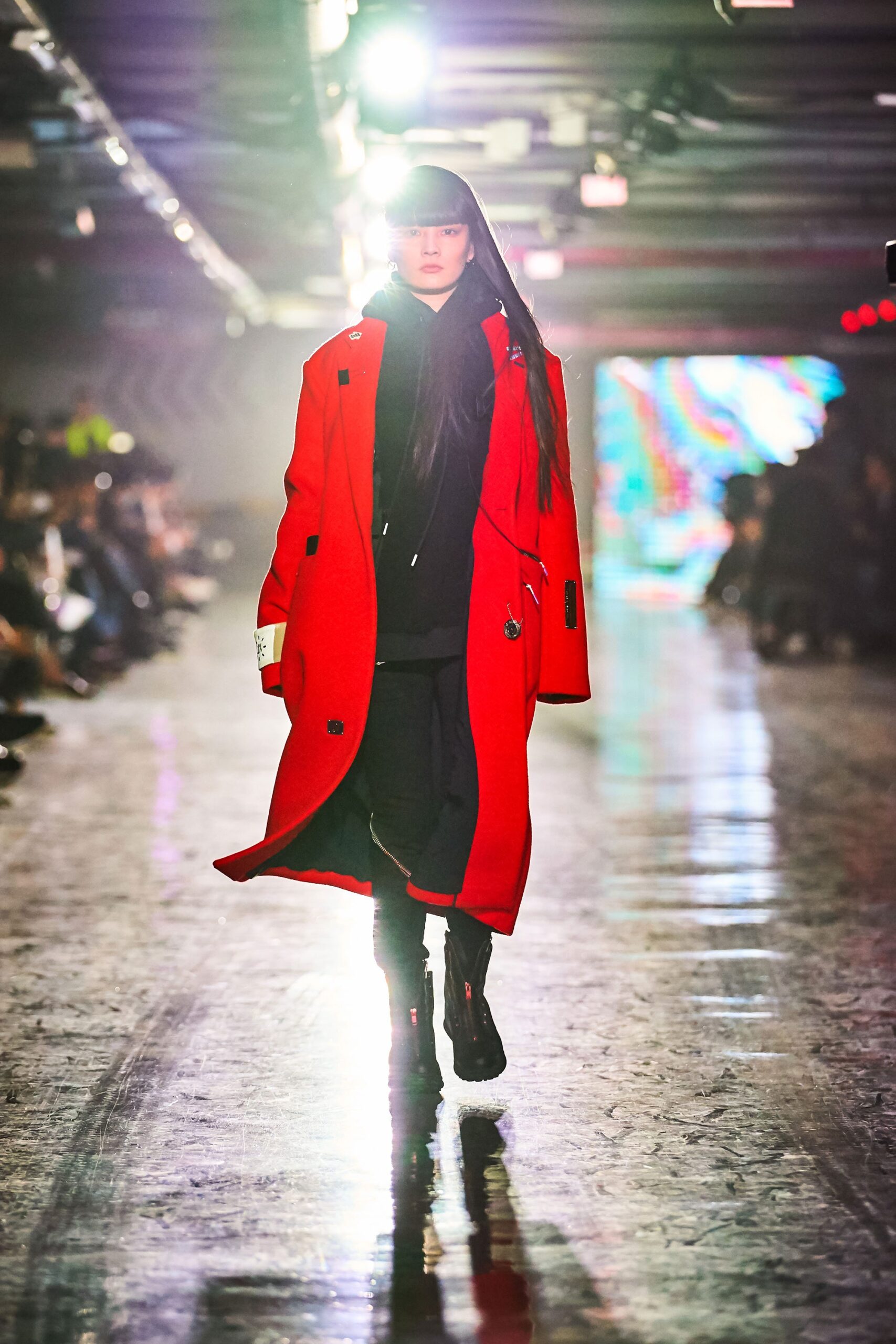 A relaxed red coat layered over a black hoodie, featuring long sleeves and buttoned details.