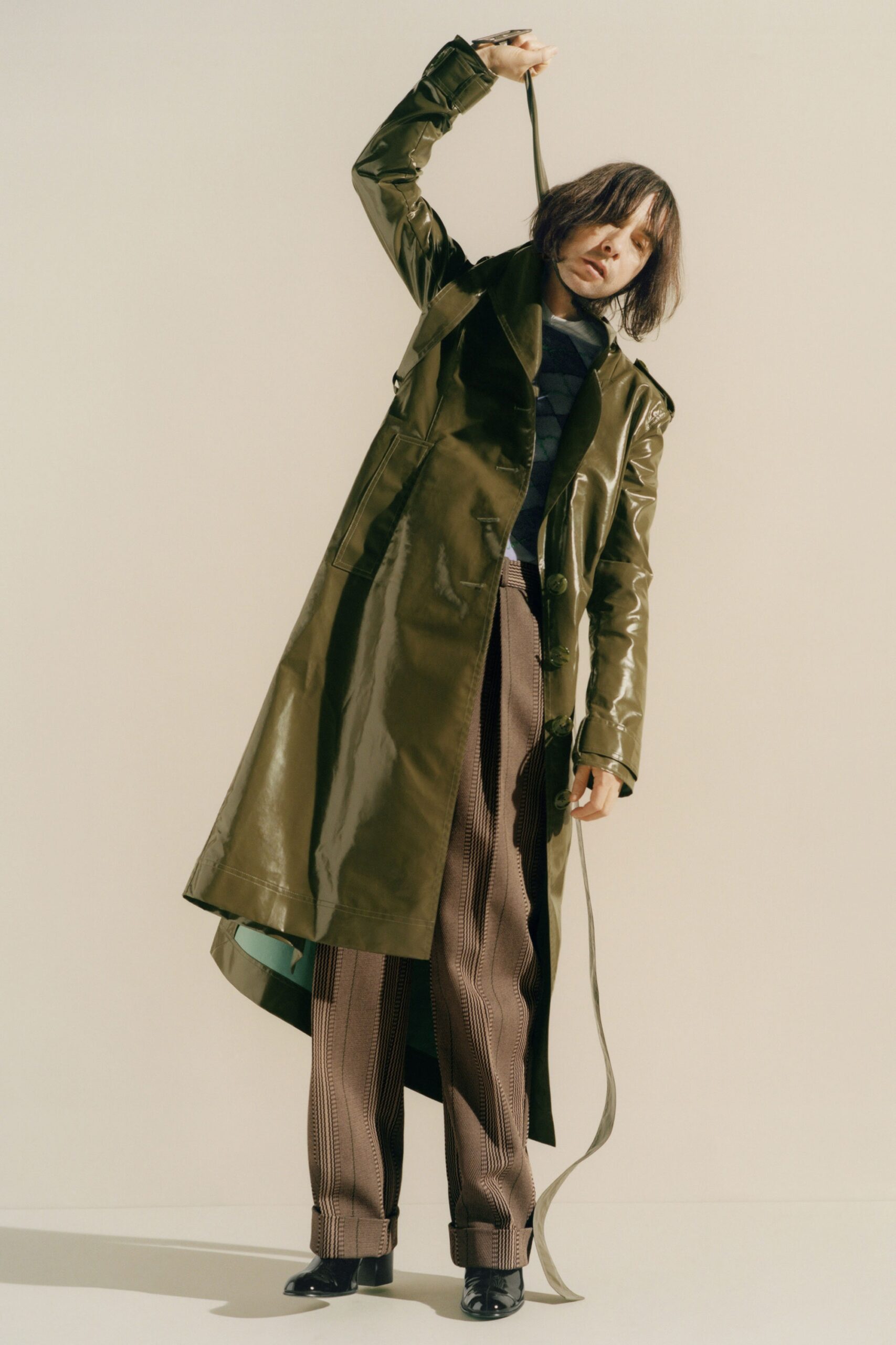 green vinyl trench coat and brown tailored pants