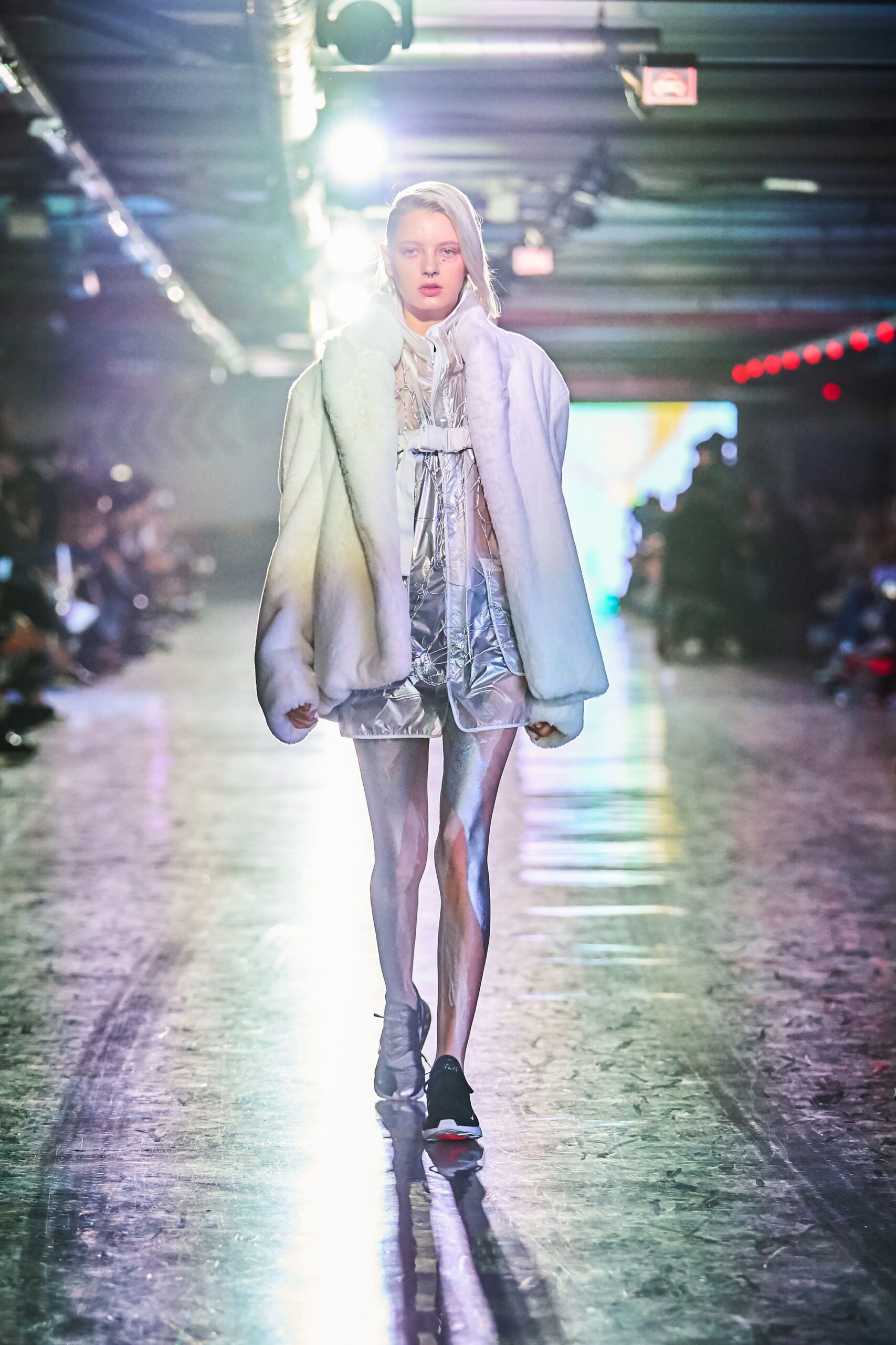 A fitted white fur coat over a sleeveless silk dress with a high neckline and layered design.