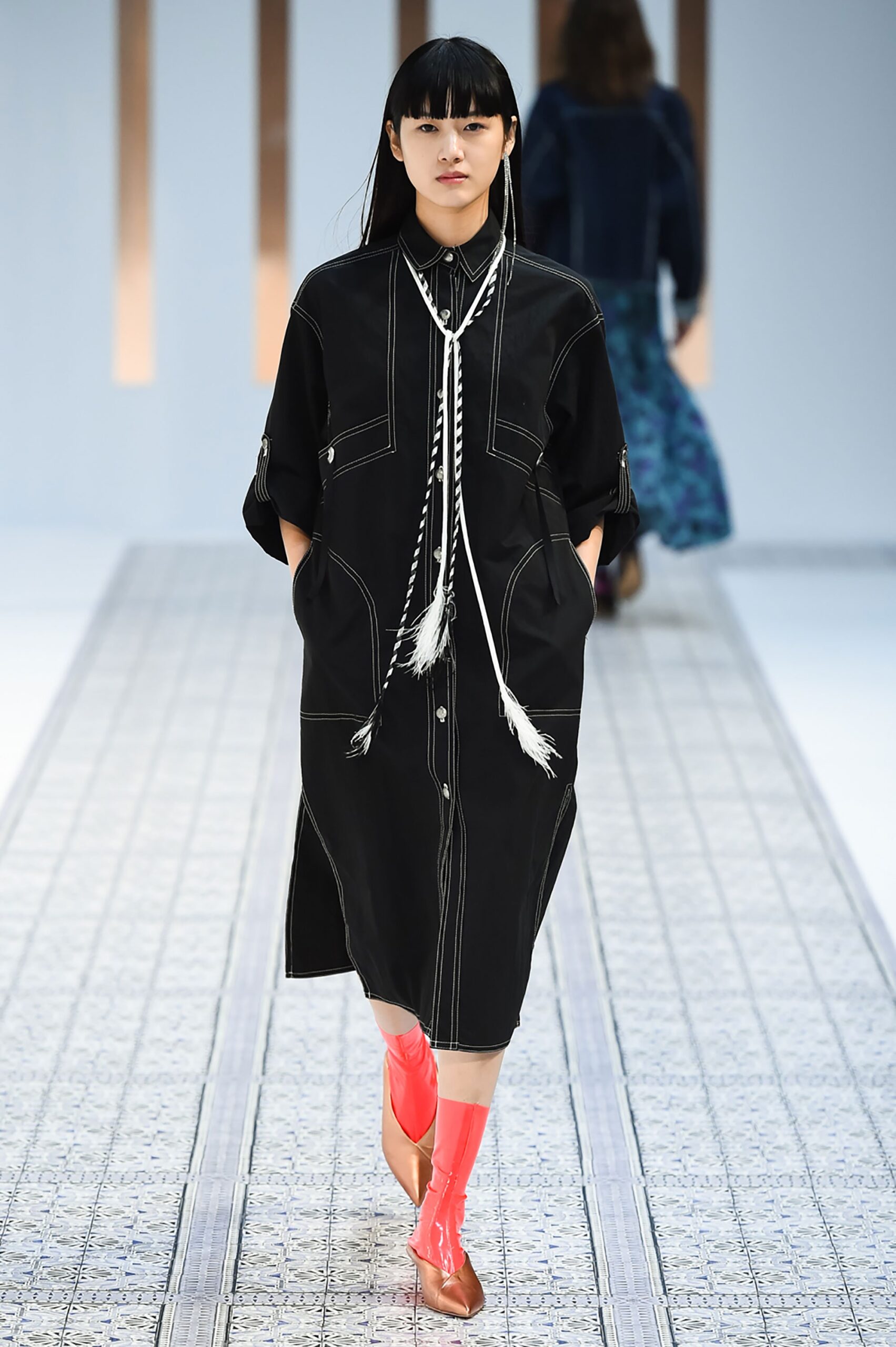 A relaxed black cotton dress with long sleeves and a collared neckline featuring button details.