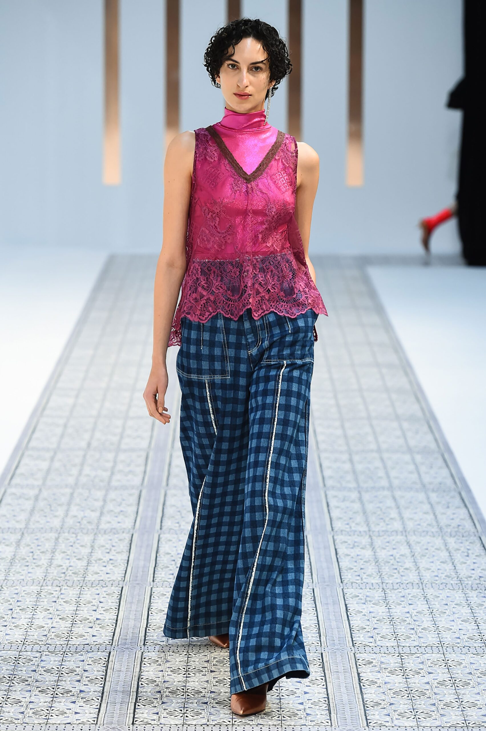 A relaxed pink lace sleeveless top paired with blue checked pants, creating a stylish ensemble.