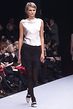 white silk sleeveless top and black pleated skirt