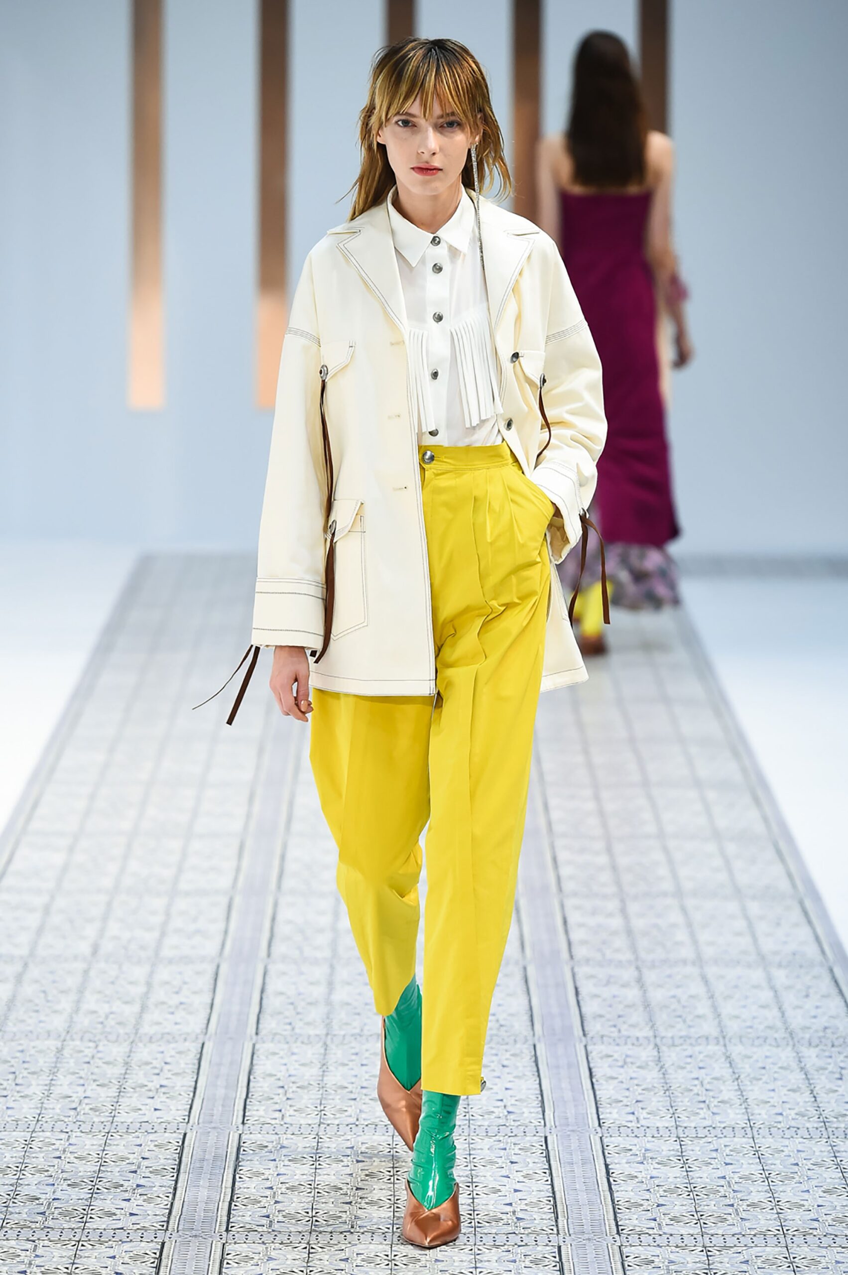 A relaxed white long-sleeve collared jacket paired with pleated yellow pants.