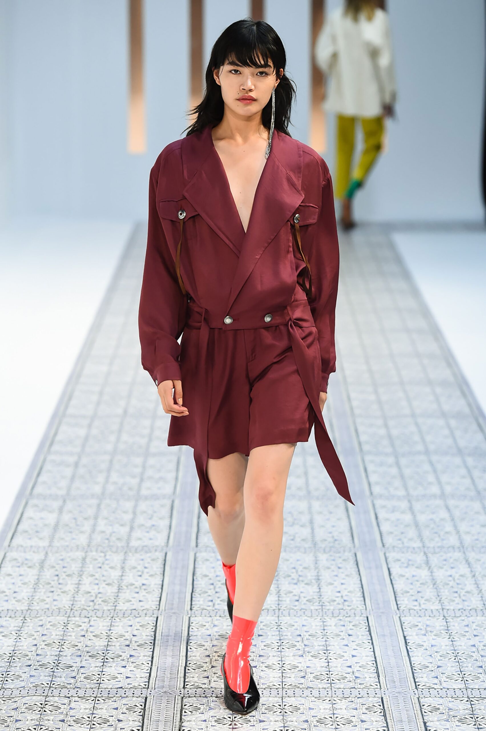 A fitted burgundy dress with a V-neckline, long sleeves, and buttoned details.