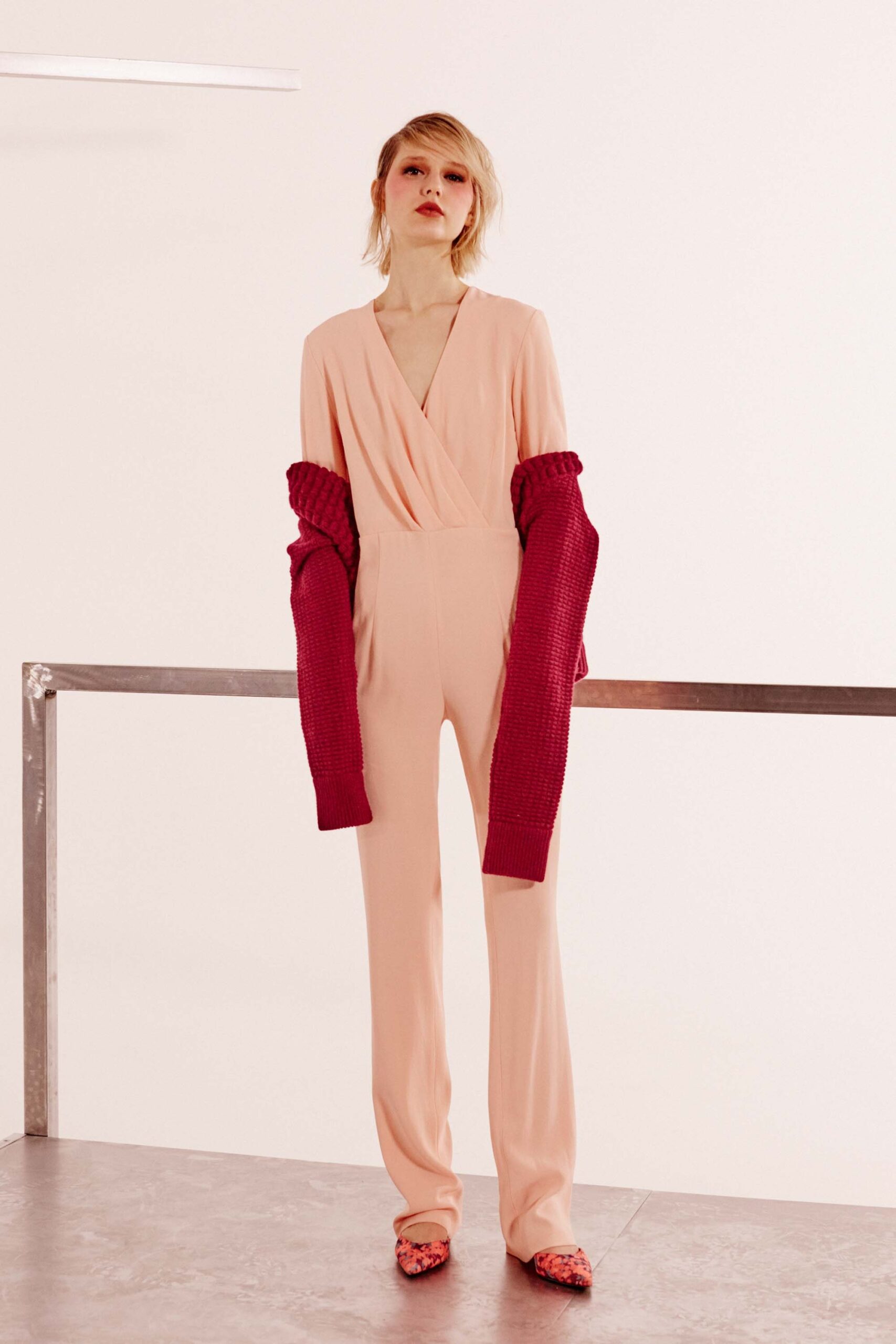 pink fitted jumpsuit with oversized red sweater