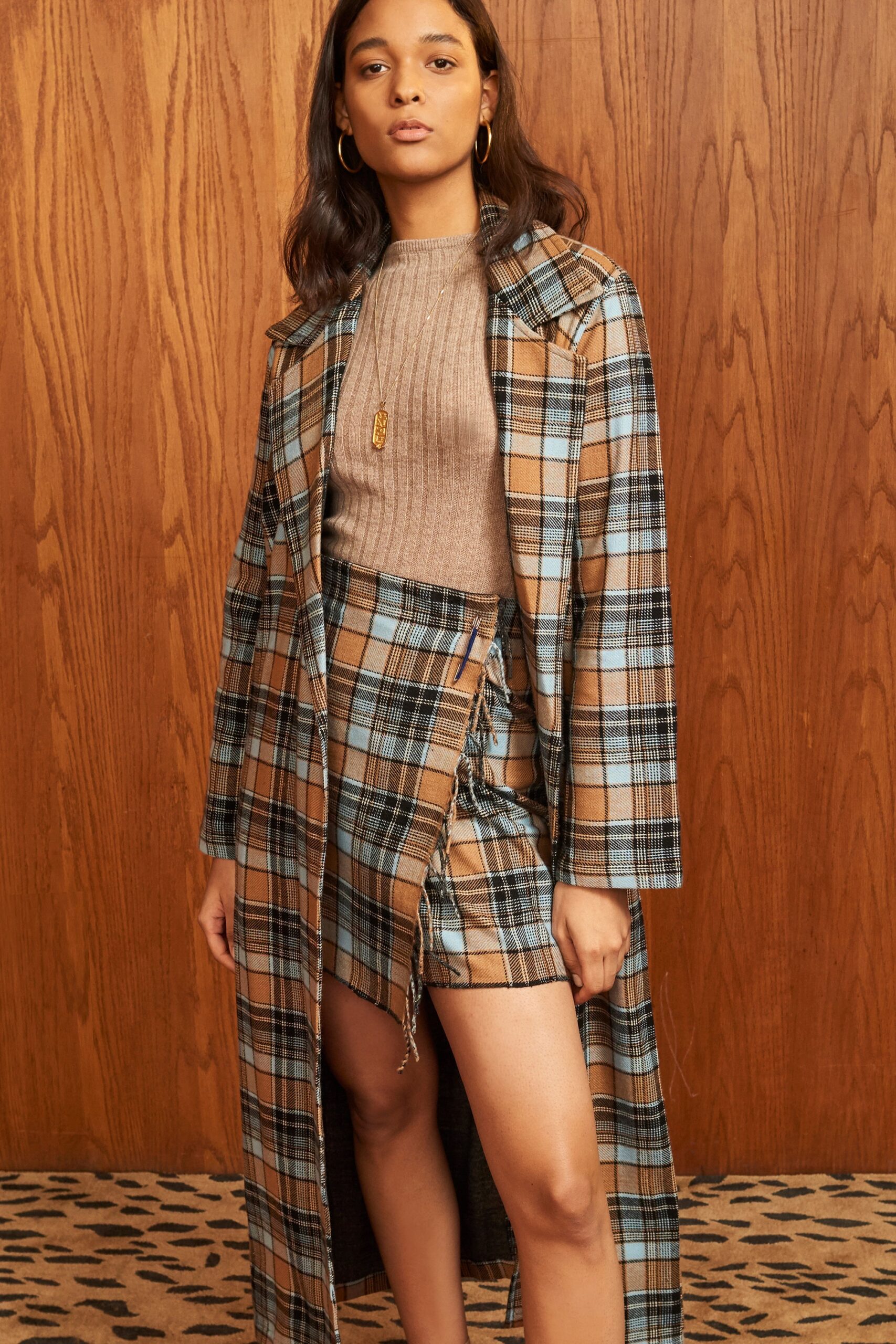 A fitted brown checked coat with a collared neckline paired with a fitted asymmetric skirt.