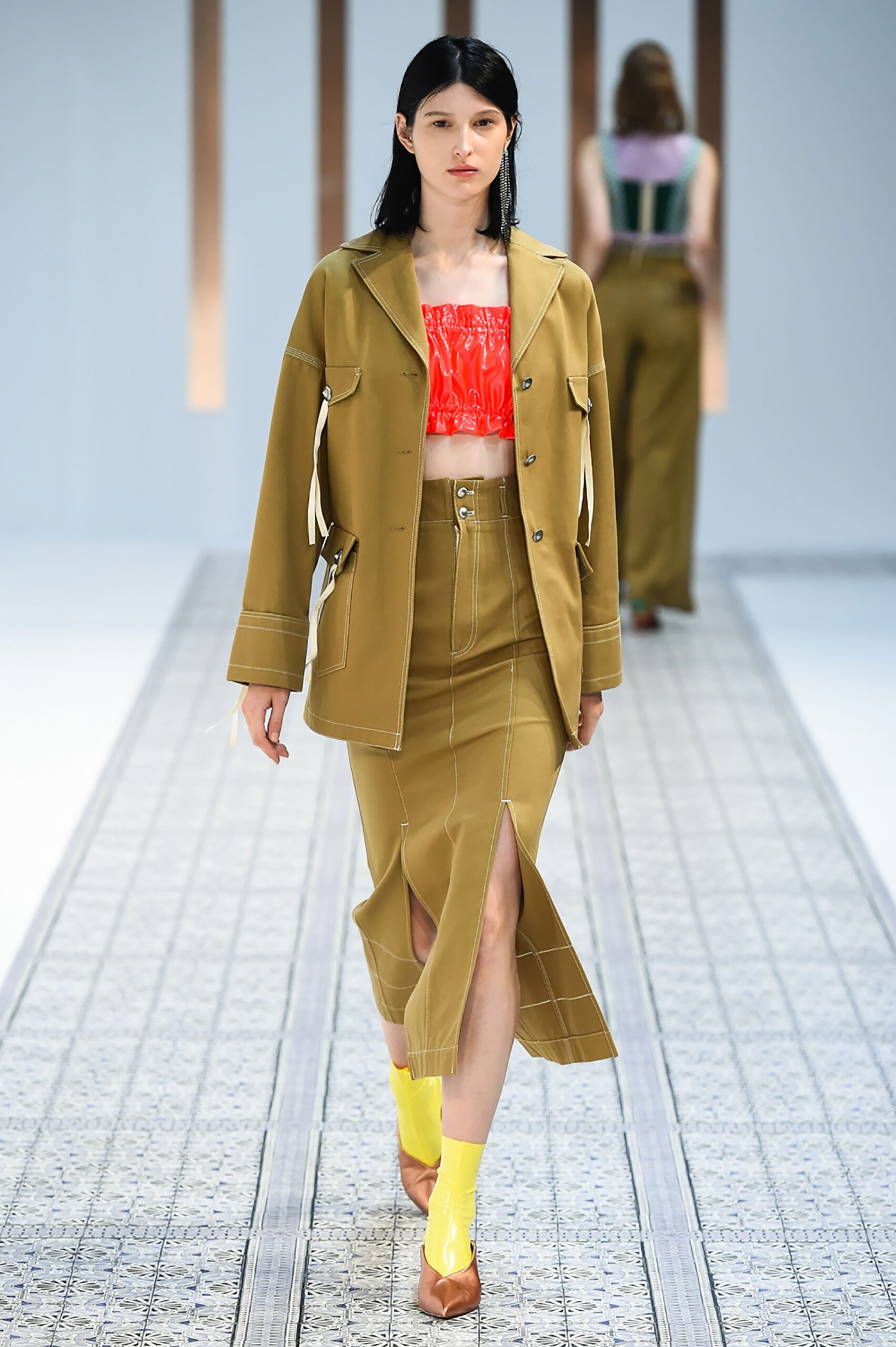 A fitted brown cotton jacket with long sleeves and a collared design paired with a slit skirt.