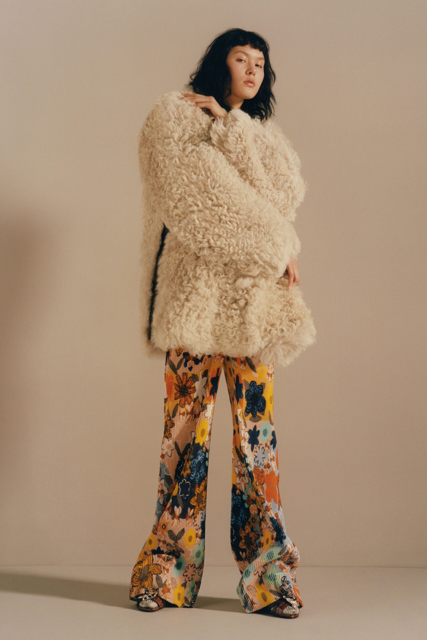 beige faux-fur coat and multi-colored flared pants