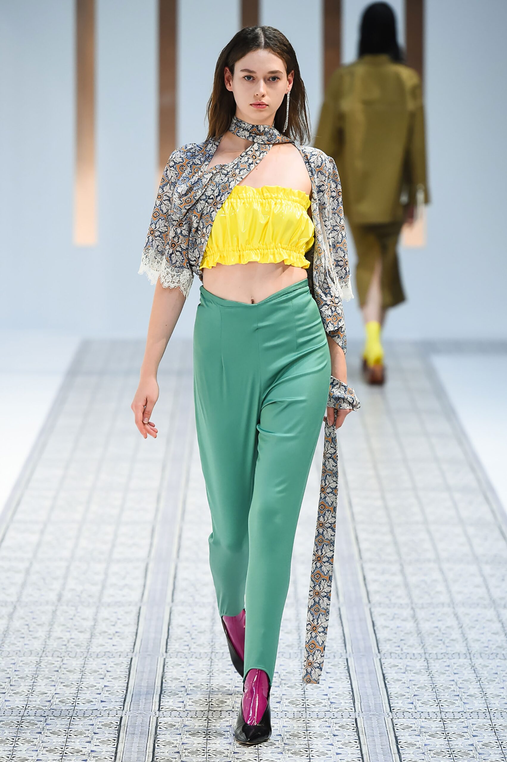 A fitted yellow sleeveless cropped top paired with high-waisted green pants.