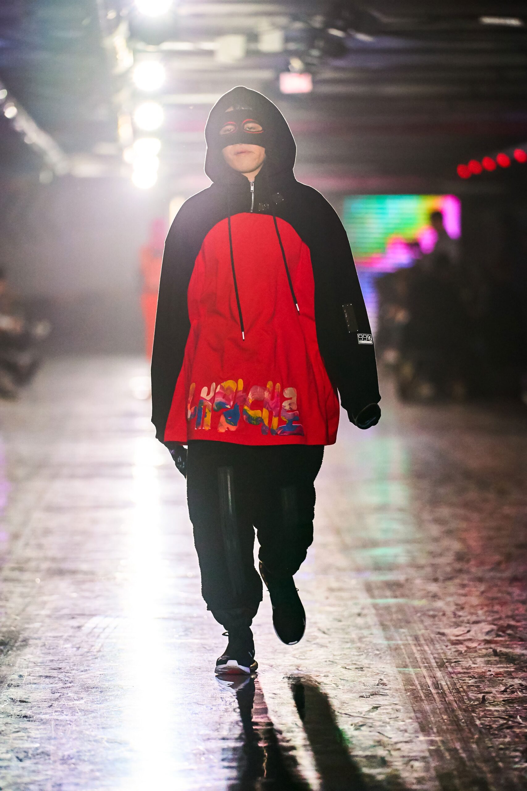 A relaxed red hoodie with long sleeves and printed details, paired with black pants.