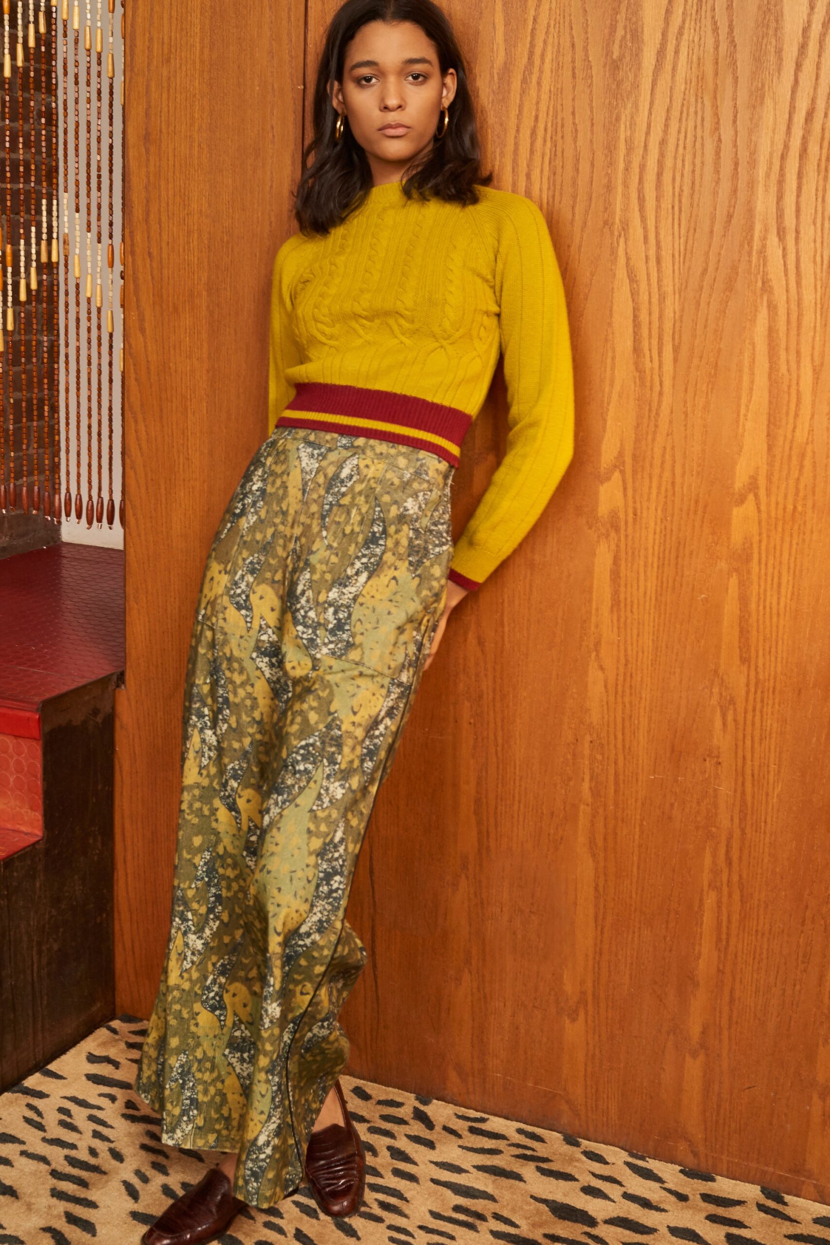 A fitted yellow top with long sleeves paired with a high-waisted printed skirt.