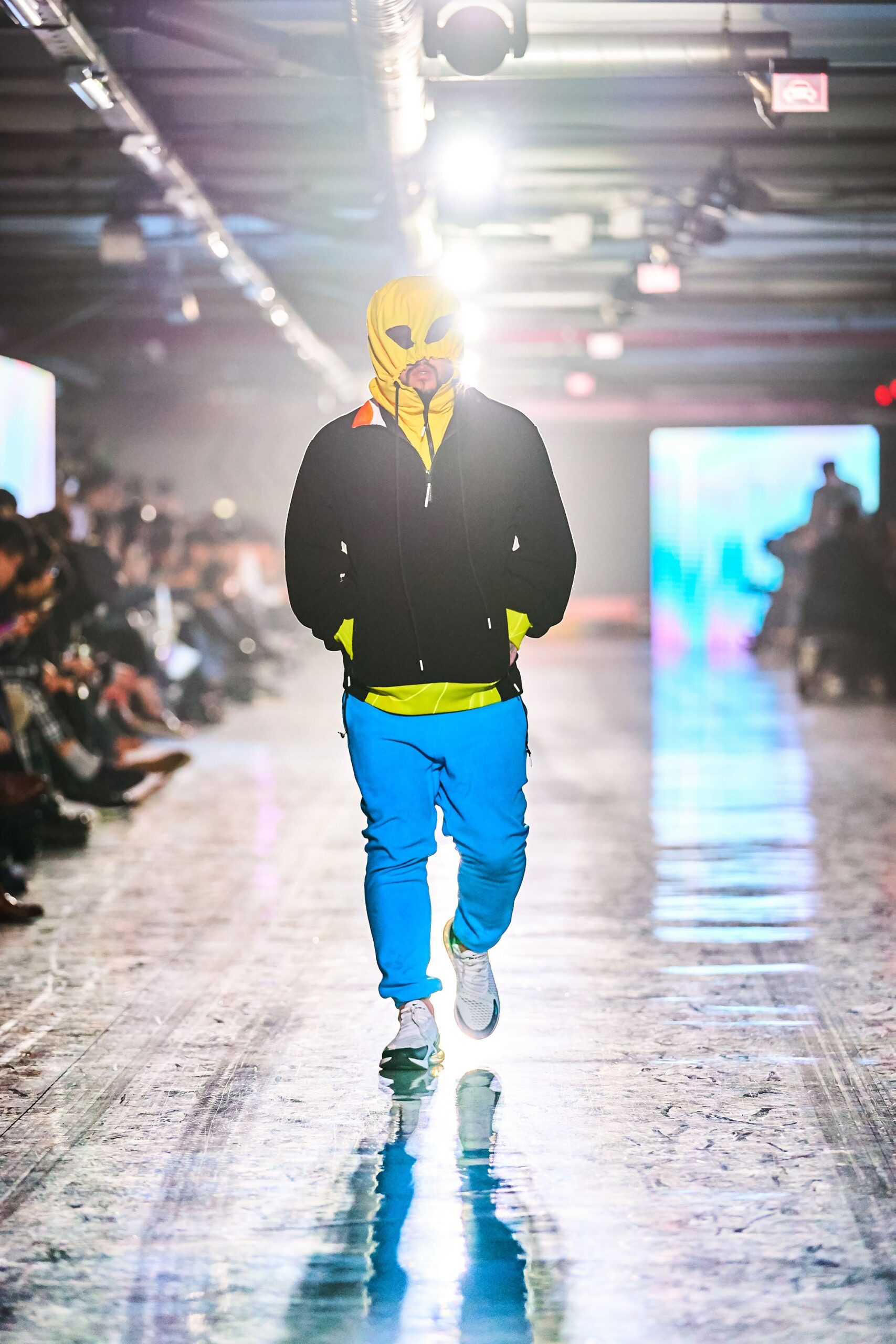 A relaxed black hooded jacket paired with blue pants, featuring a zippered design.