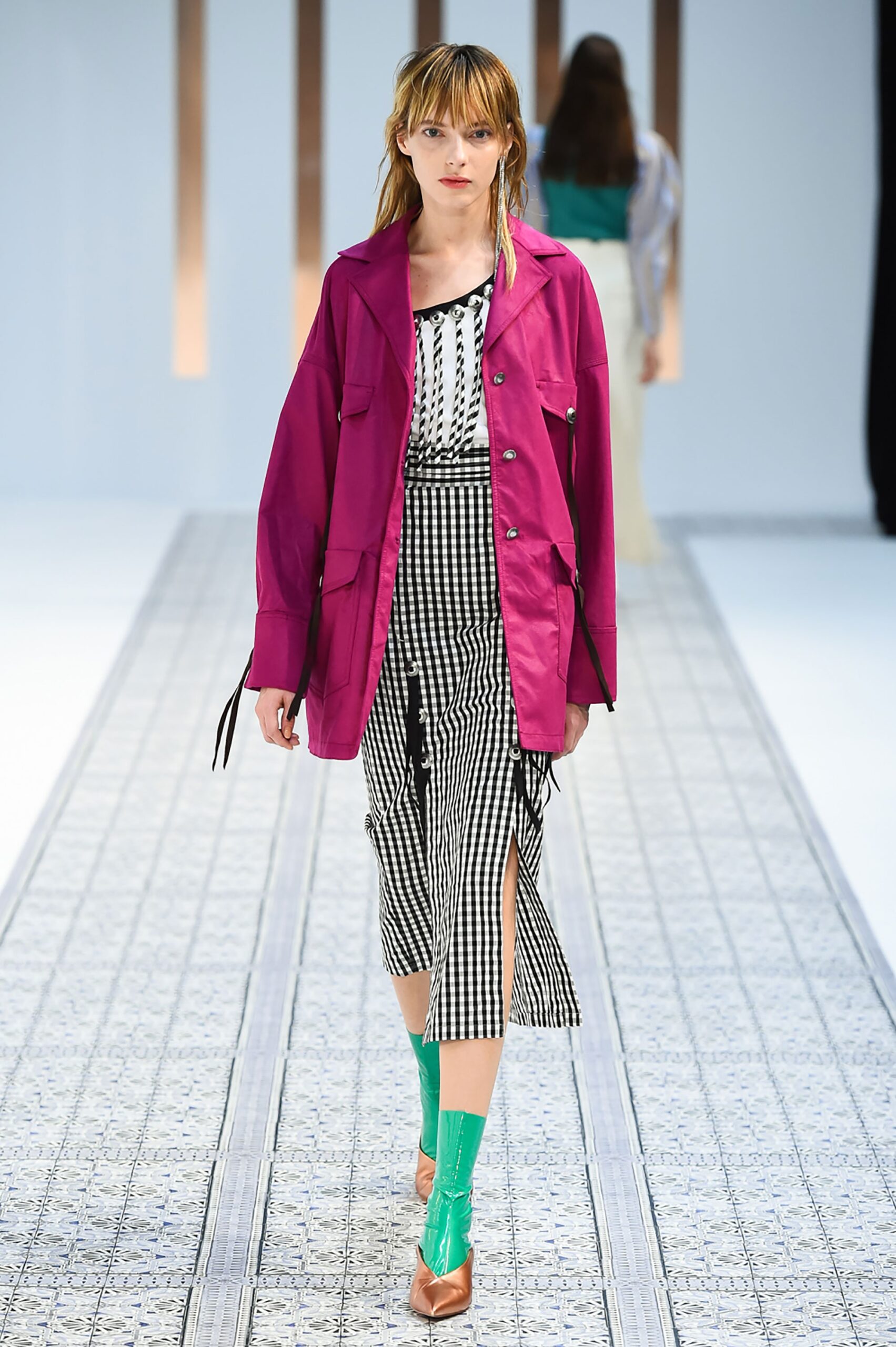 A fitted pink jacket layered over a black and white striped dress with an asymmetric design.