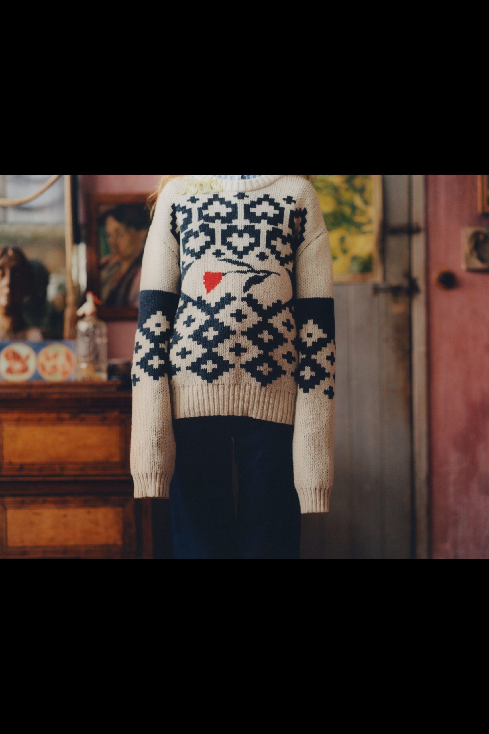 beige embroidered wool sweater and blue jeans