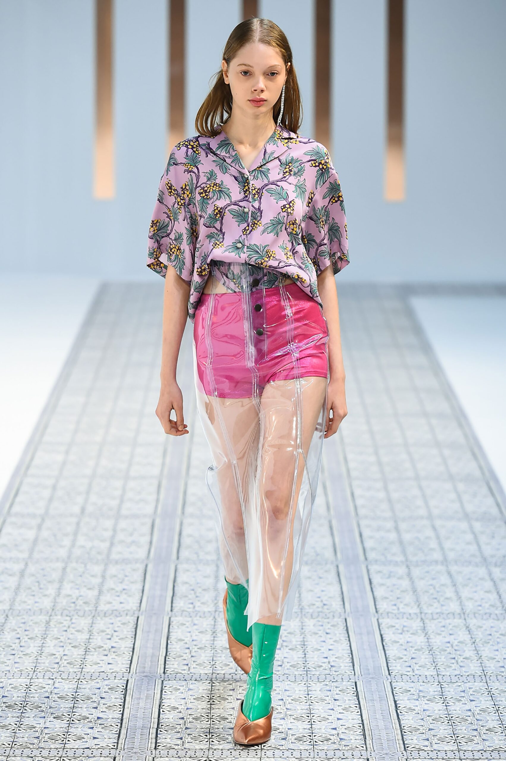 A relaxed pink printed top paired with high-waisted green shorts made from plastic material.