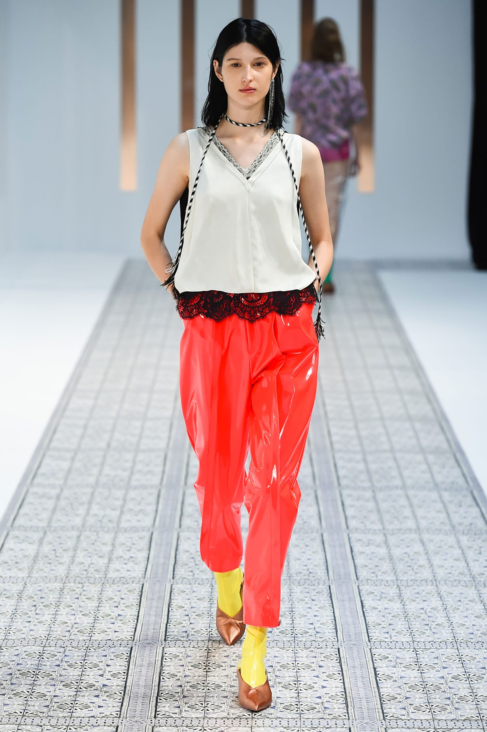 A relaxed white sleeveless top paired with vibrant red pants, featuring an asymmetric design.