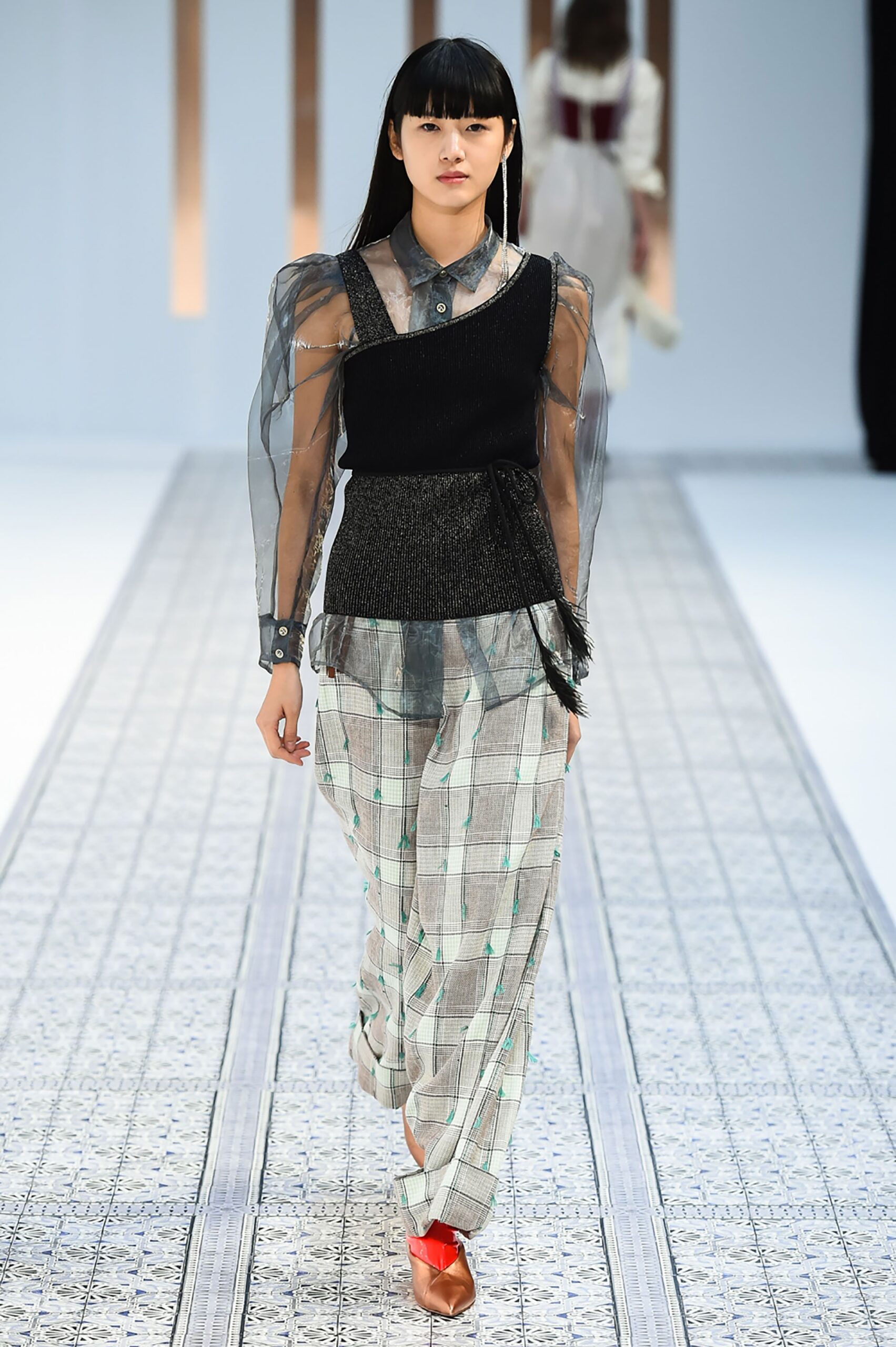A fitted black and white long-sleeve top with layered details paired with checked pants.