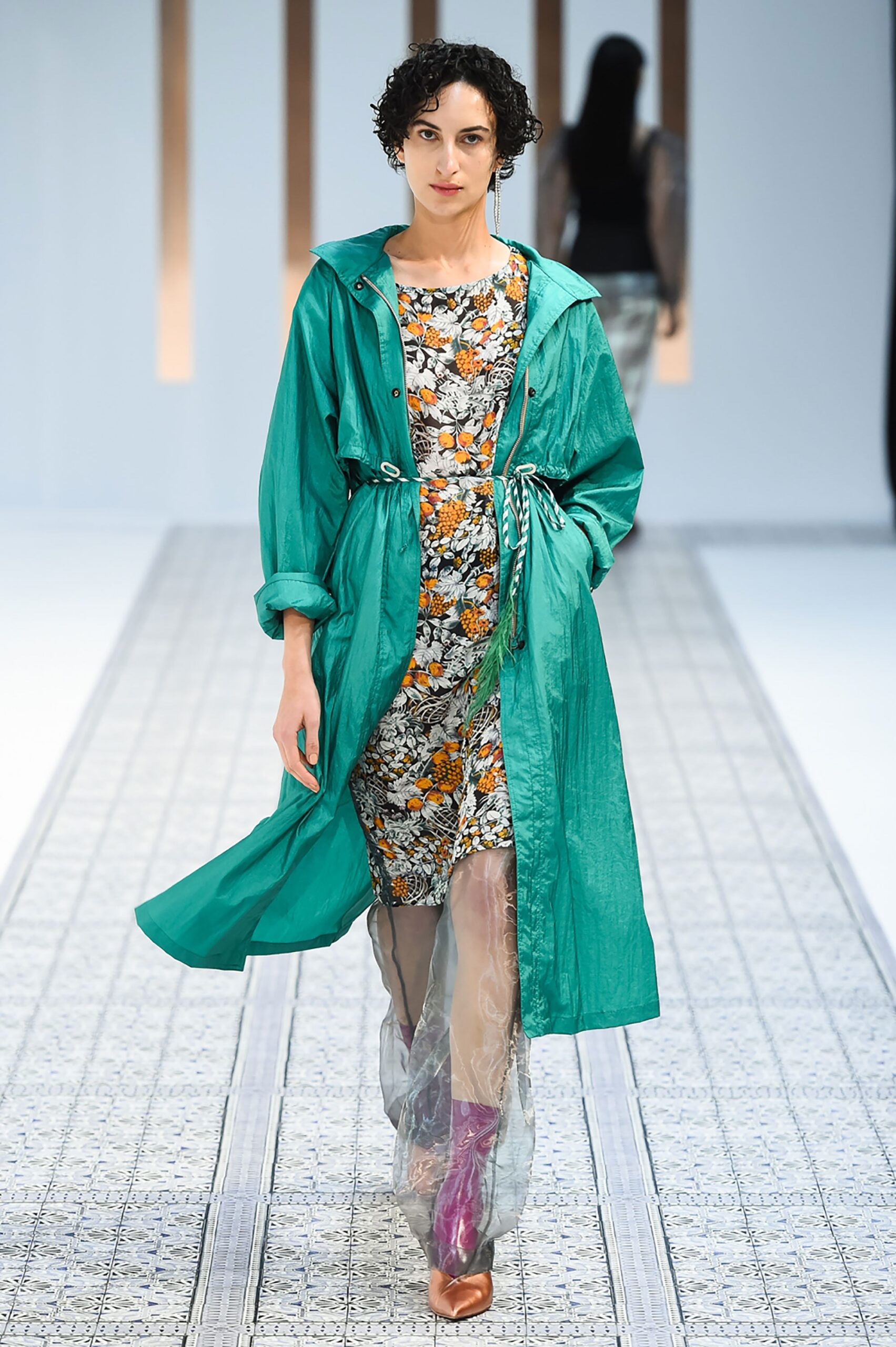 A fitted floral dress layered under a green coat, perfect for a stylish runway look.