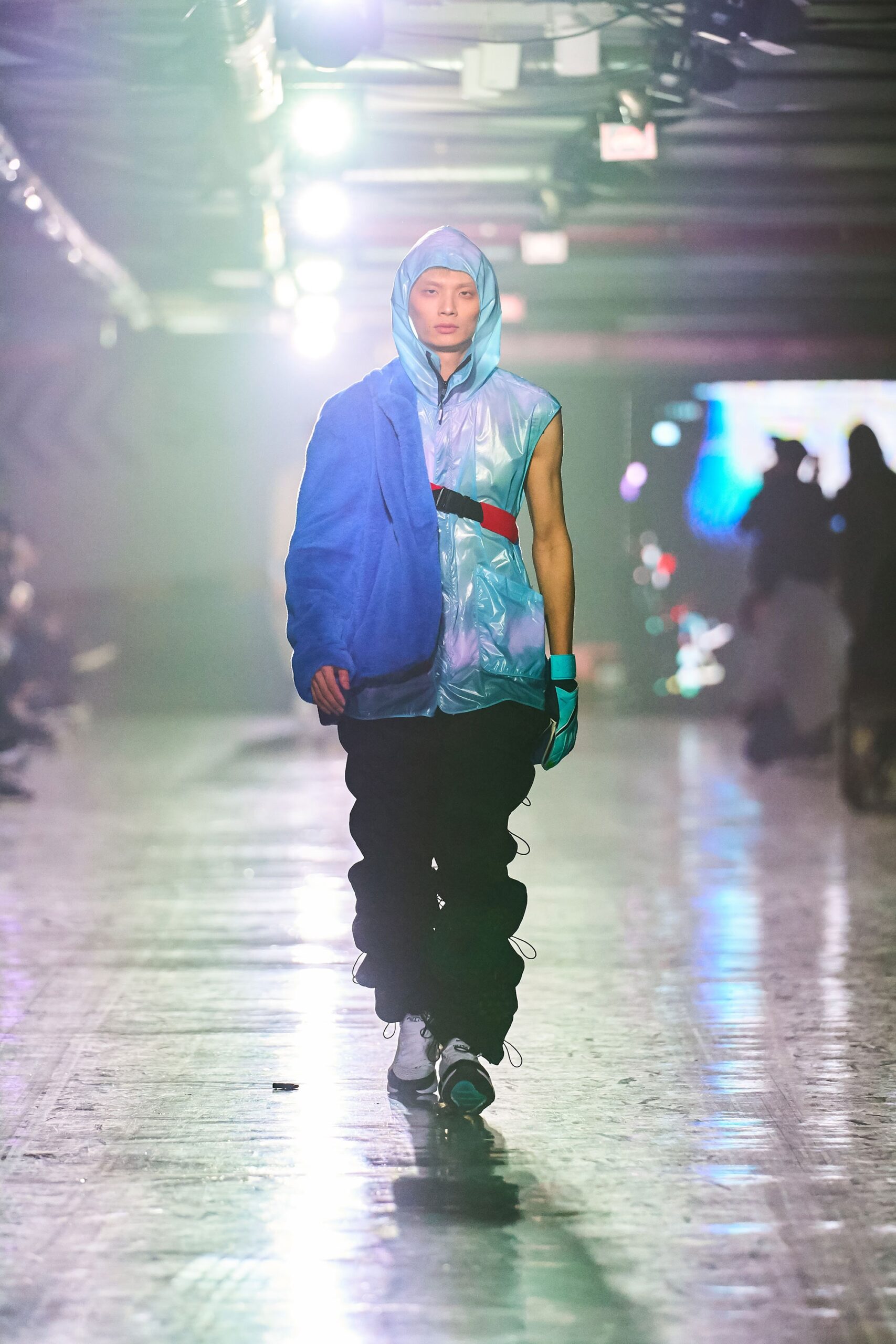 A relaxed blue nylon jacket layered over a sleeveless top paired with black pants.