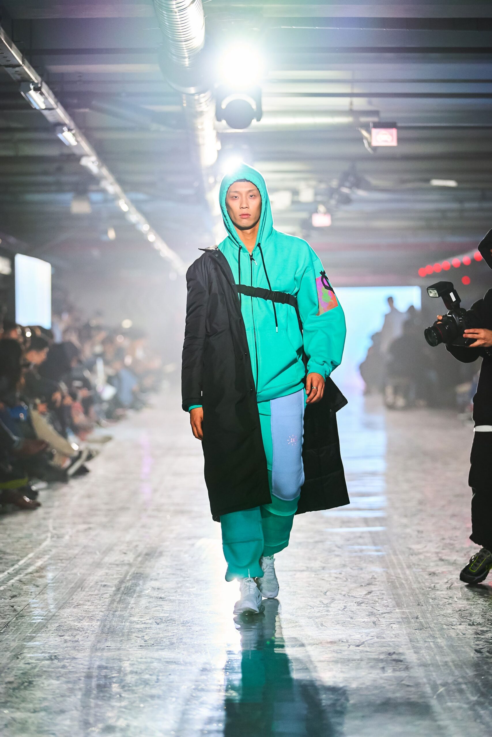 A relaxed black hooded jacket paired with green pants featuring a zippered detail.