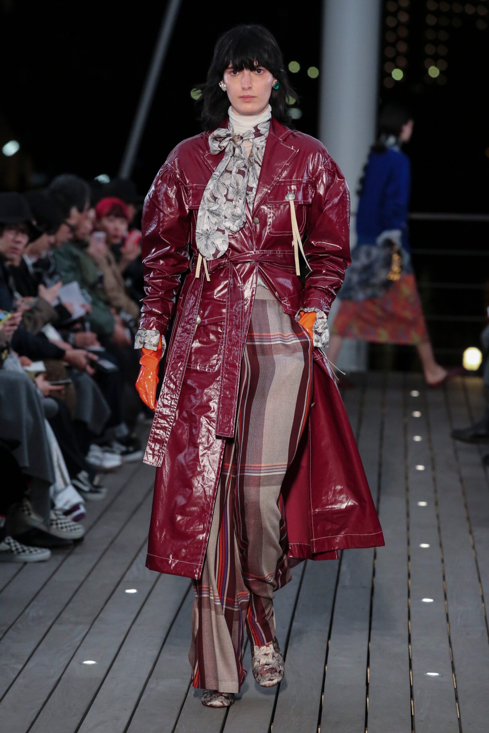 A fitted red leather coat paired with plaid pants, featuring a collared design and layered details.