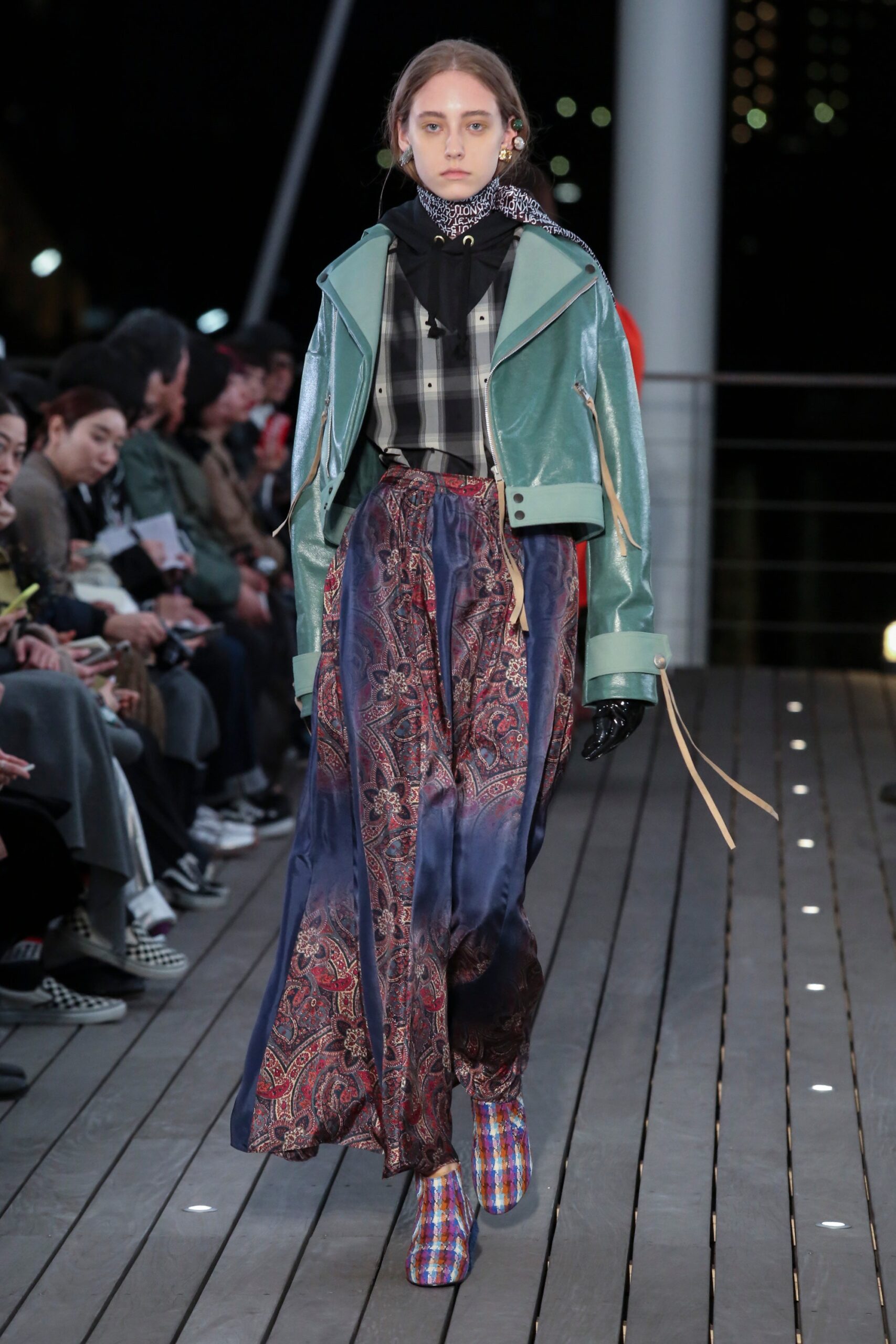 A relaxed green leather jacket paired with a flared printed skirt for a stylish runway look.