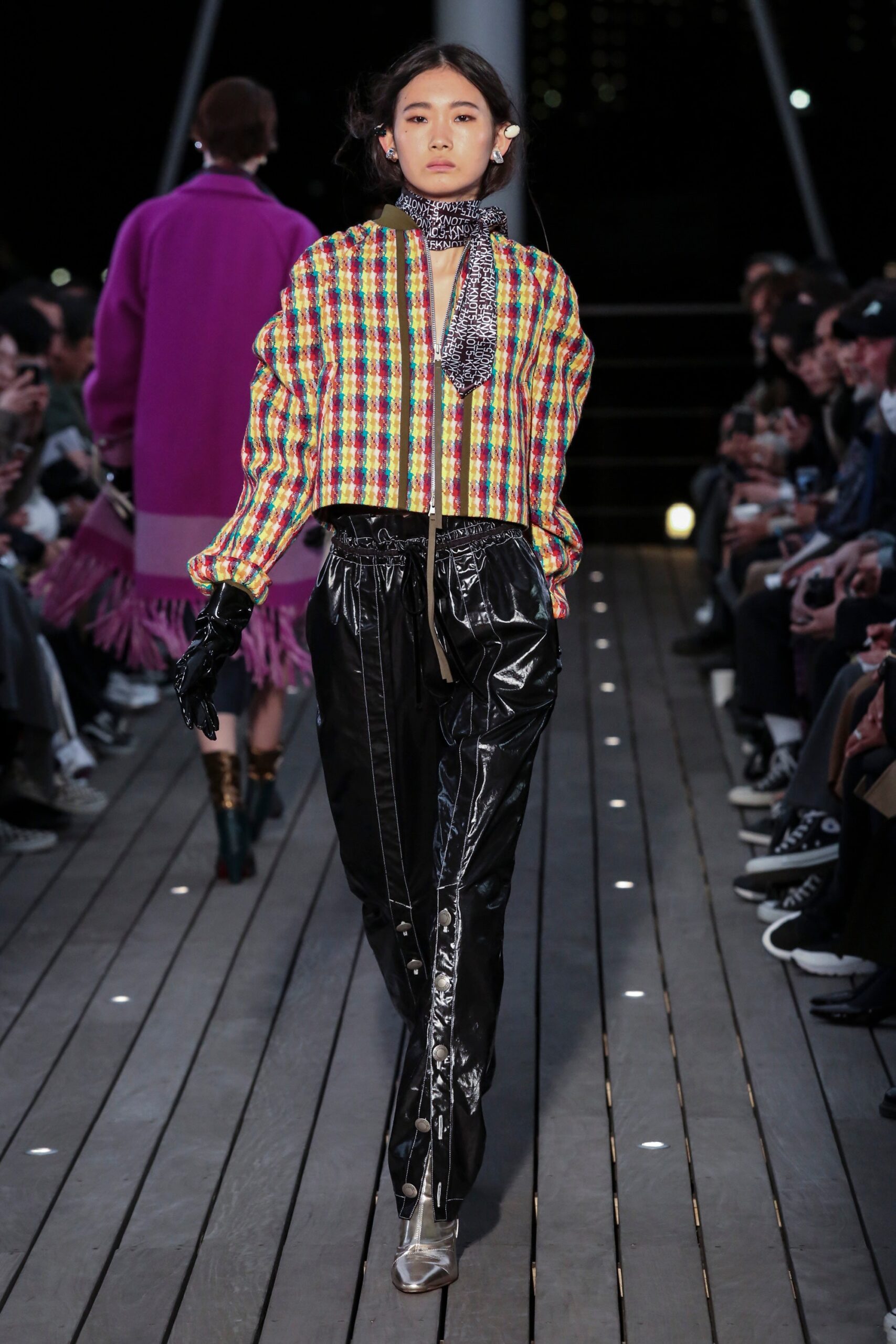 A relaxed multicolor jacket with long sleeves paired with black leather pants featuring zippered details.