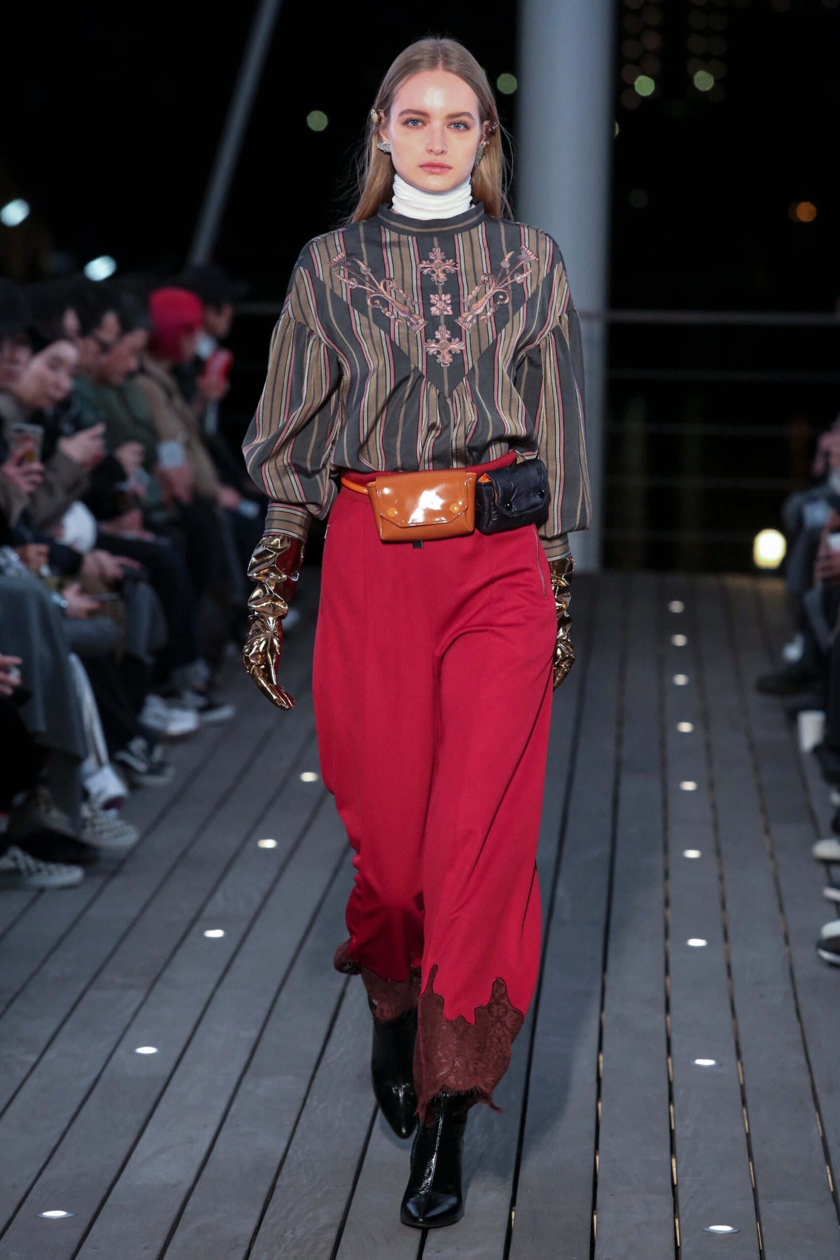 A relaxed striped blouse with long sleeves and embroidered details paired with red pants.