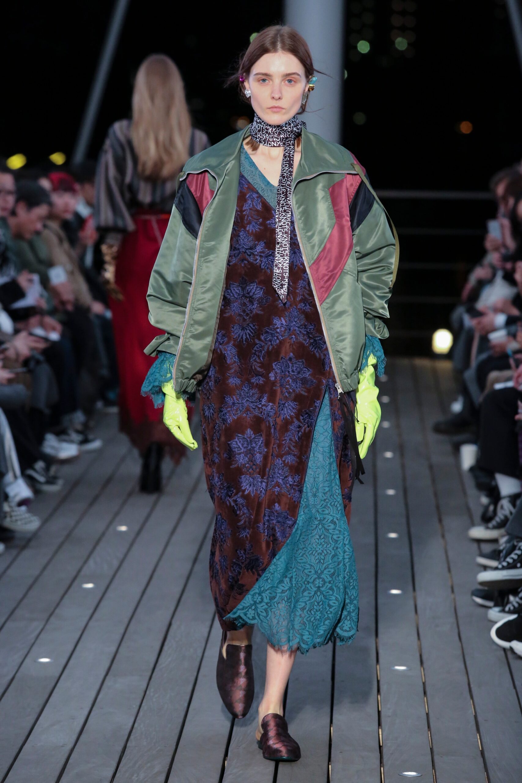 A relaxed layered printed dress paired with a collared jacket in black, green, and blue hues.