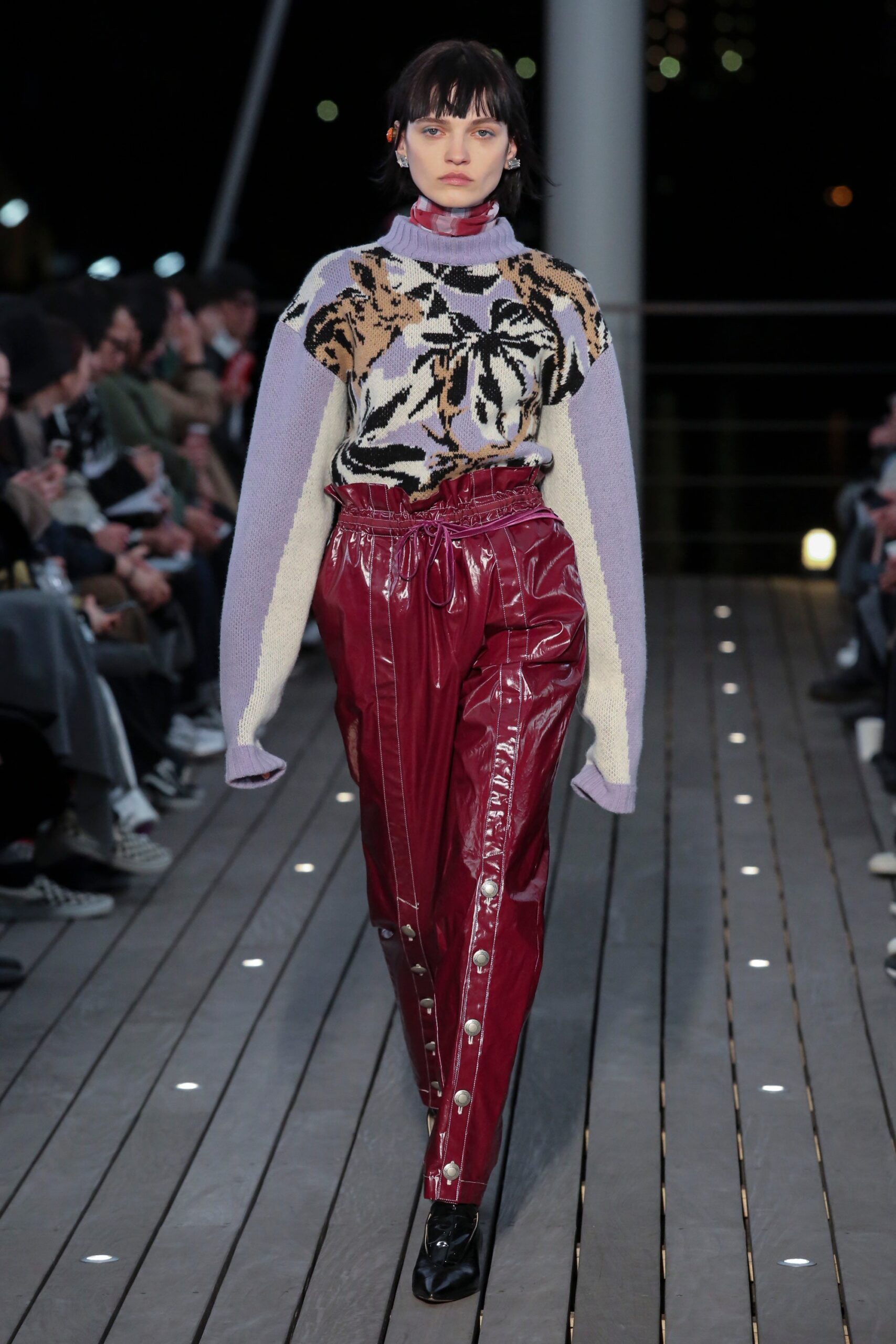 A relaxed fit purple printed sweater paired with red zippered pants.