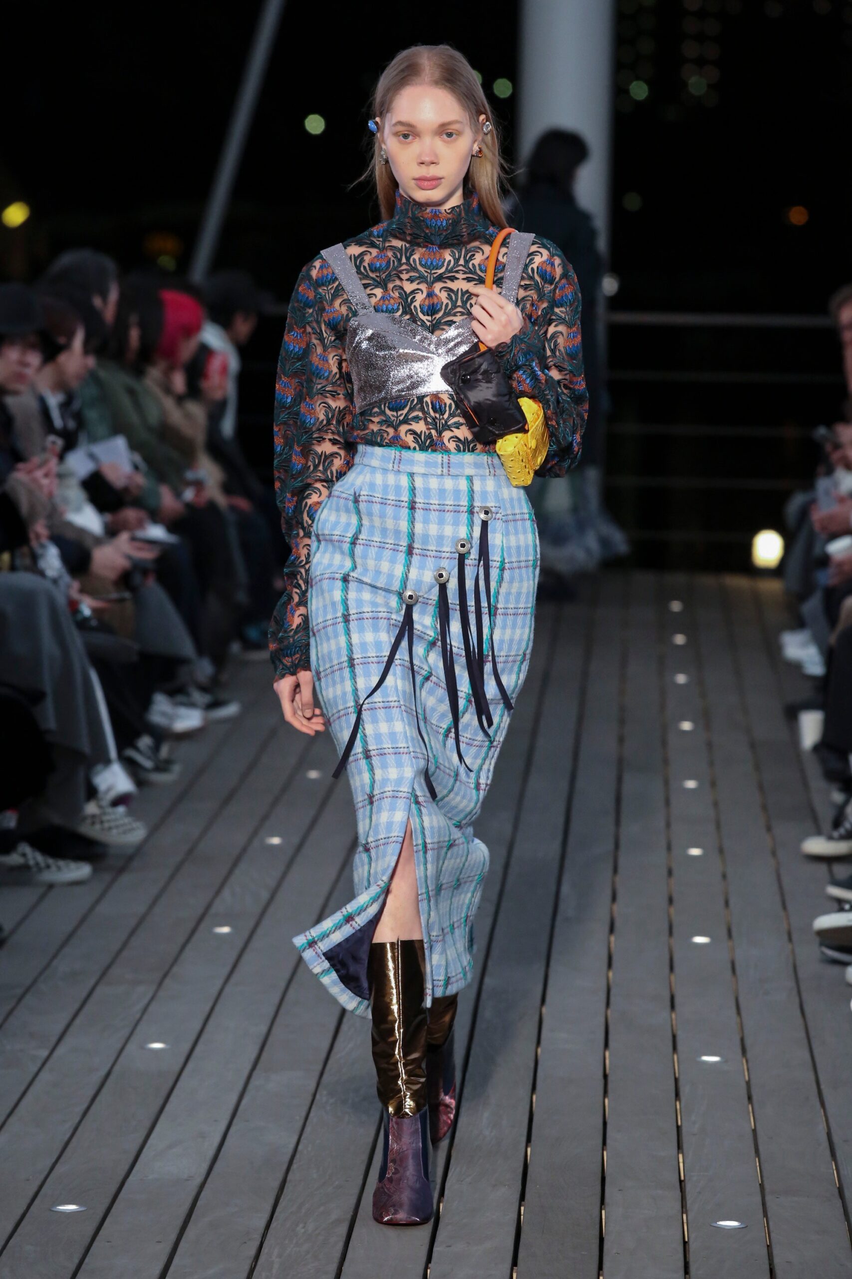 A fitted black long-sleeve top with a V-neck paired with a blue plaid skirt featuring a slit.
