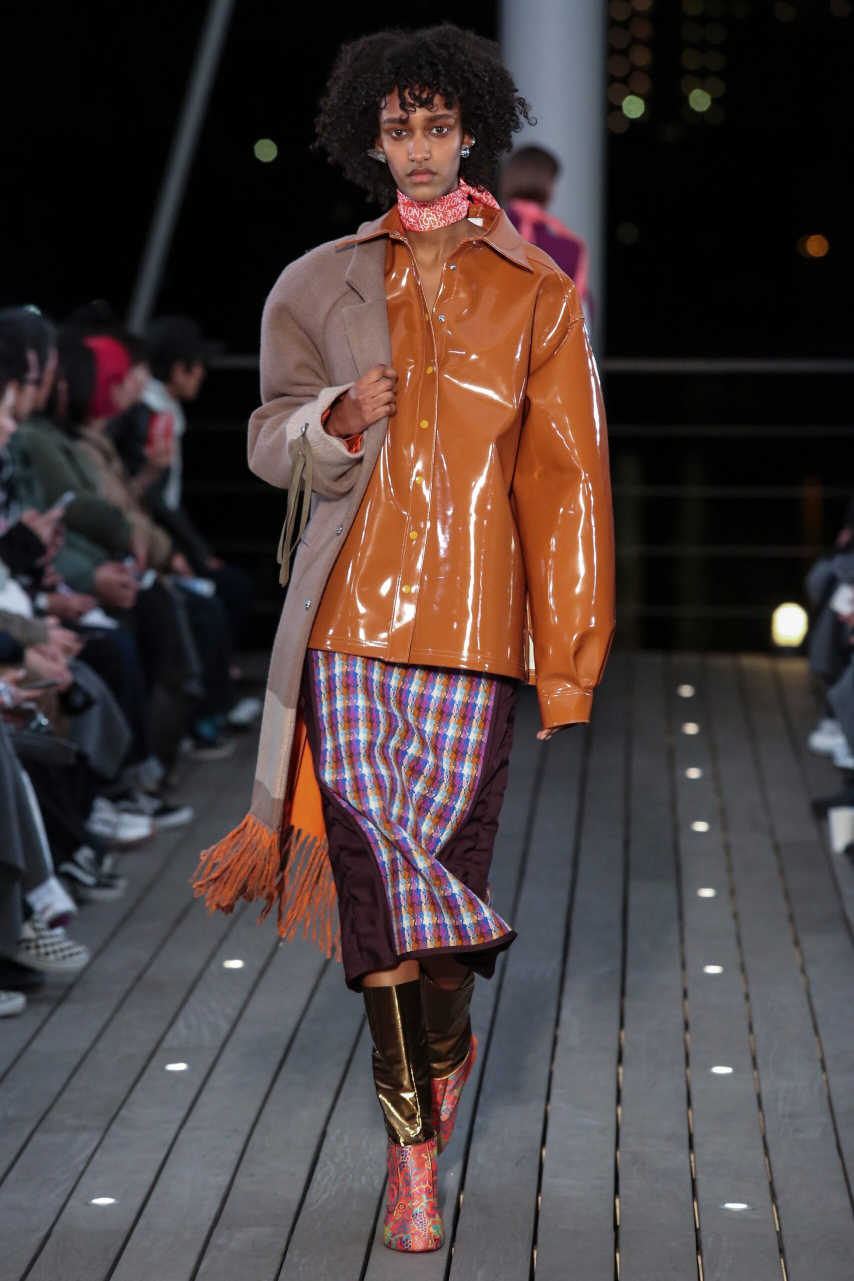 A relaxed orange leather coat layered over a checked shirt, featuring long sleeves and a collared design.