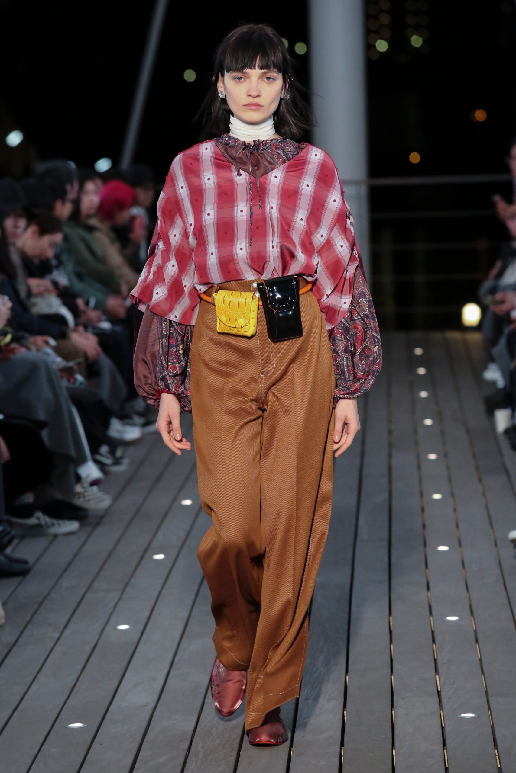 A relaxed red printed top with long sleeves paired with wide-leg brown pants.