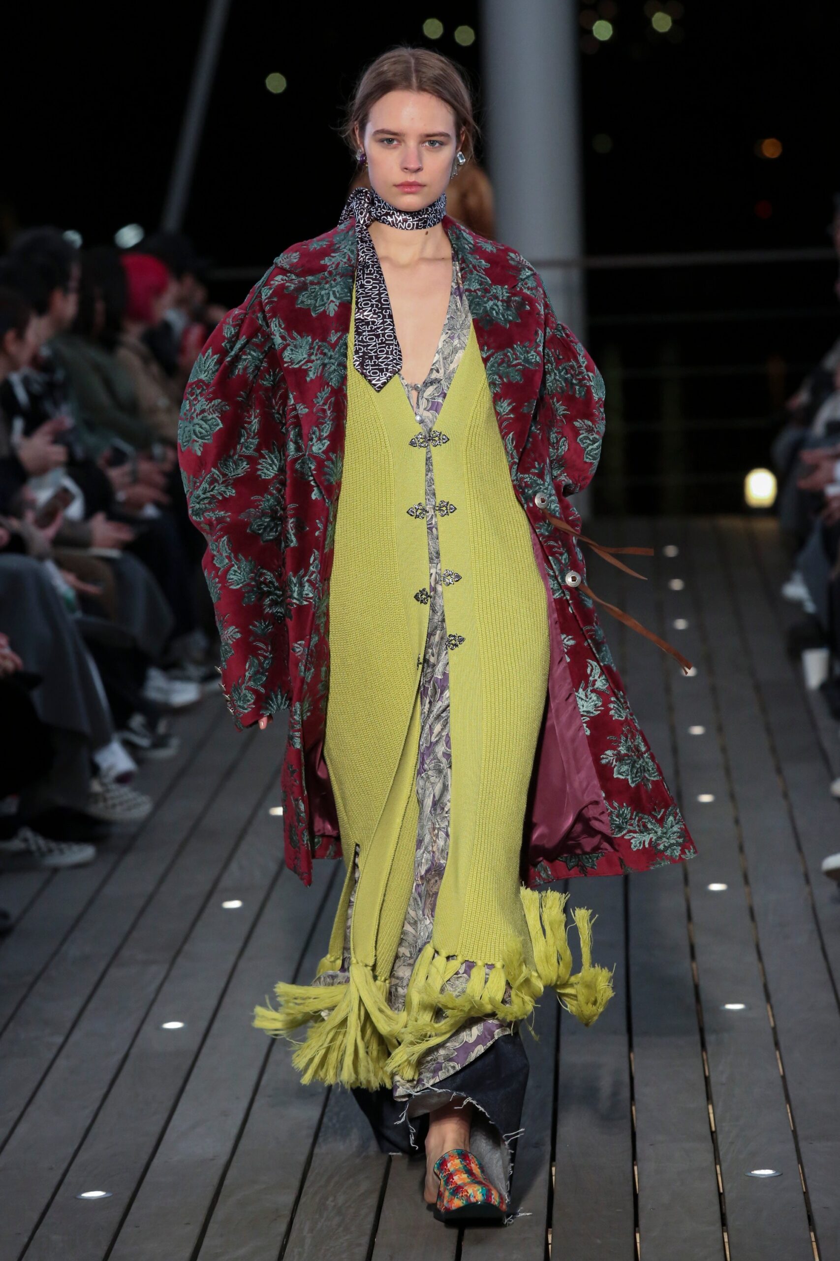 A relaxed green sleeveless dress with a V-neckline and layered flared design, complemented by a red floral coat.