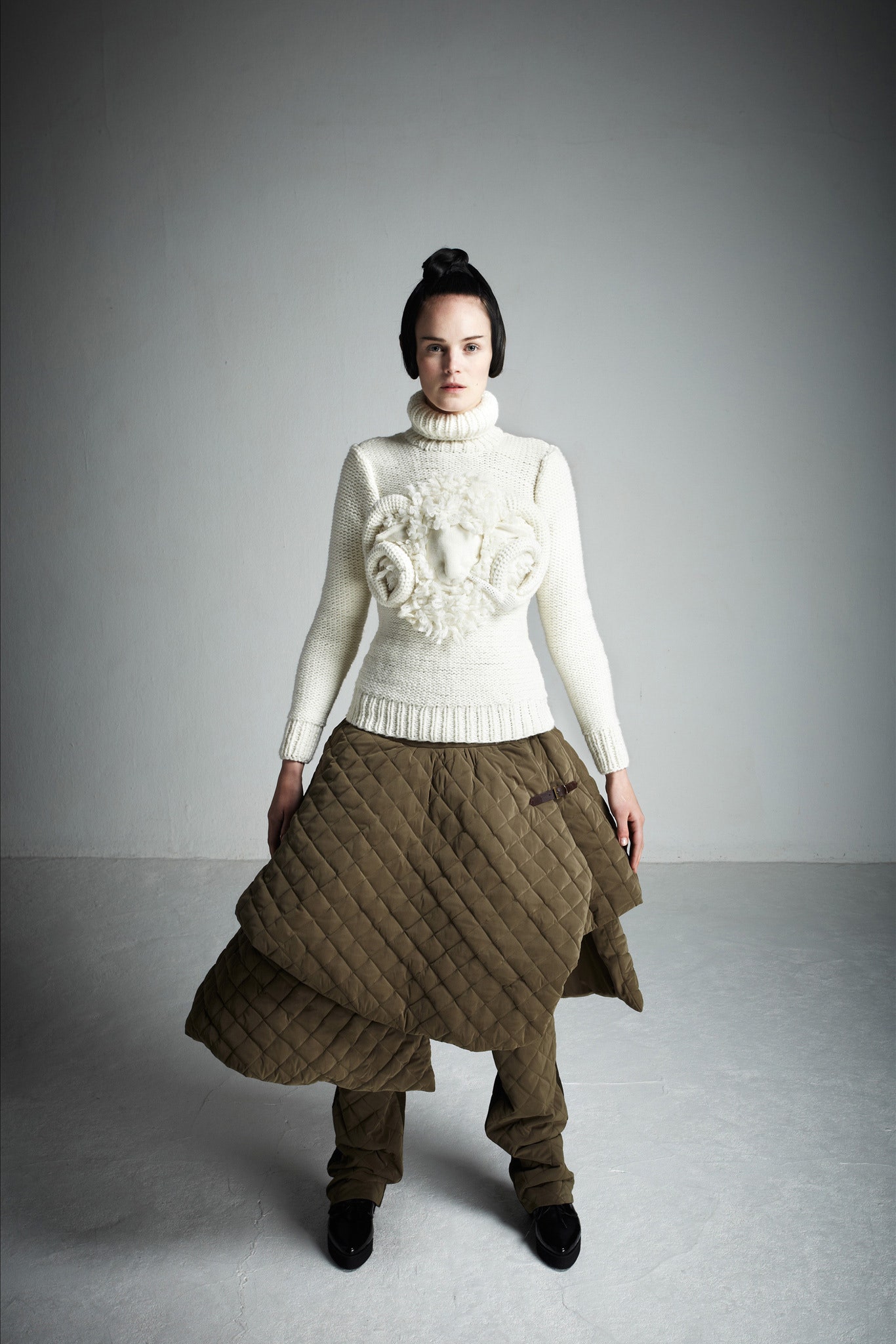 white wool sweater with embroidery and brown quilted pants