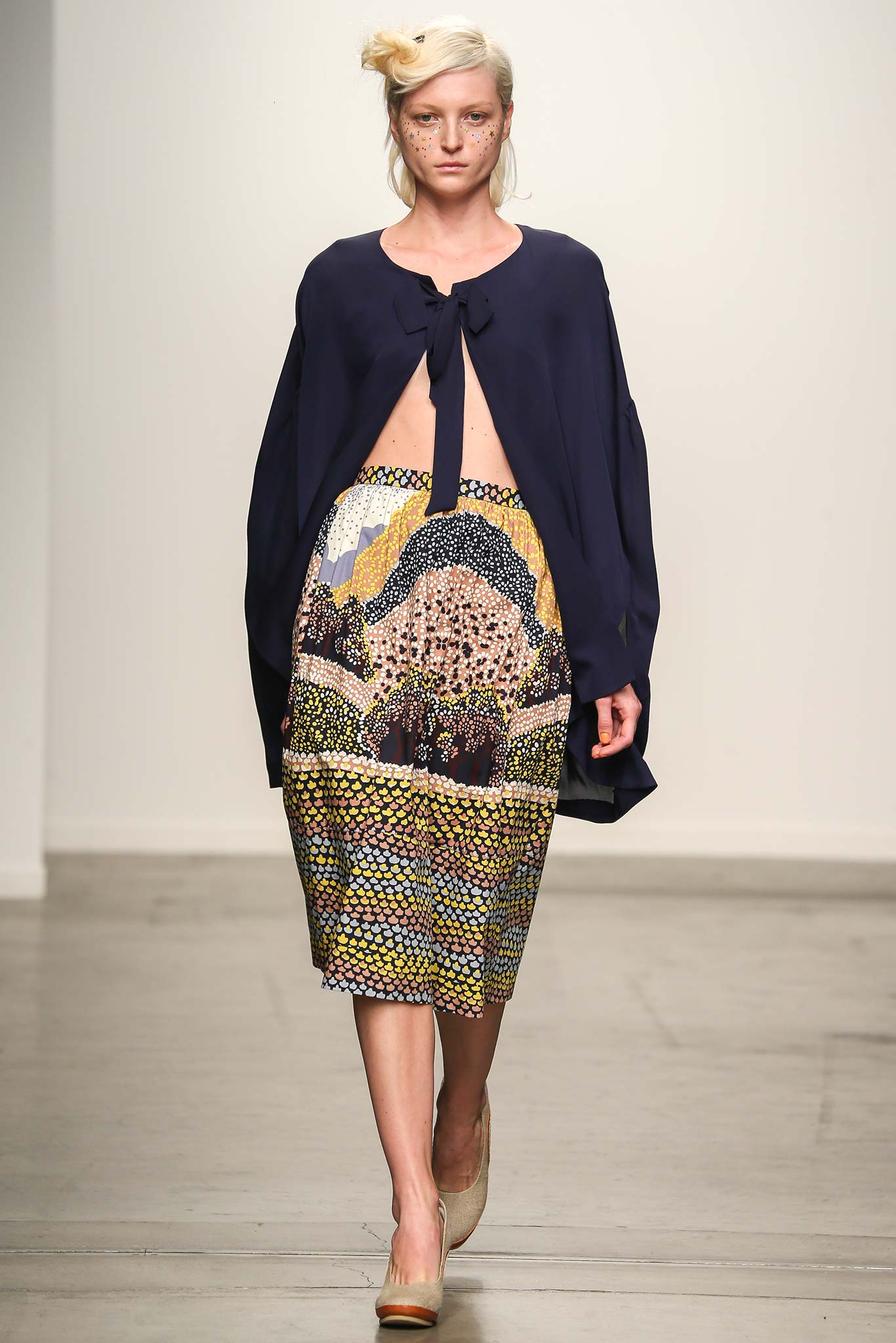 A relaxed blue long-sleeve blouse with a collar paired with a multicolor printed skirt.