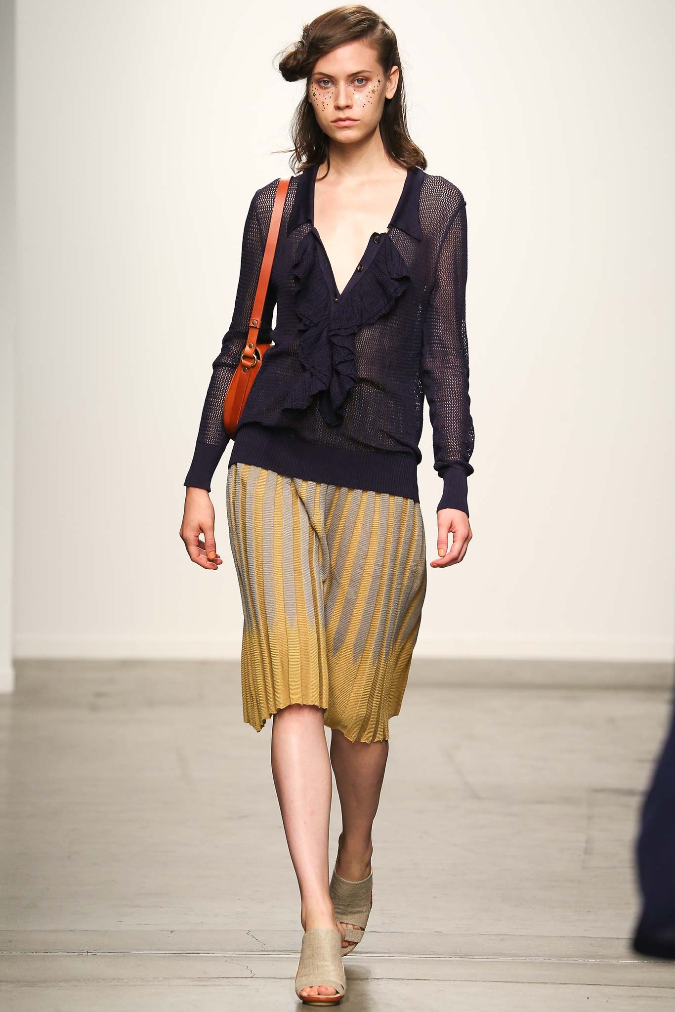 A fitted navy long-sleeve top with a V-neck and a pleated yellow skirt featuring stripes.