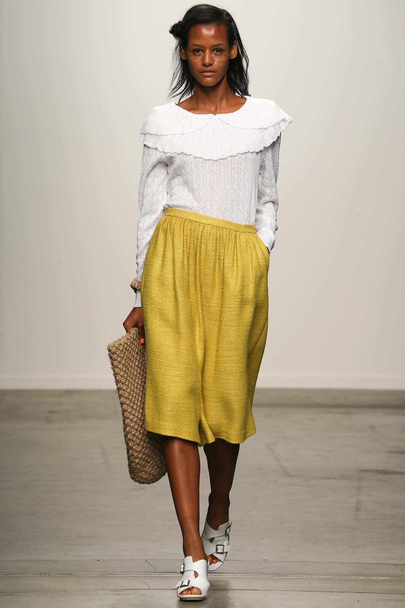 A relaxed white long-sleeve blouse with a collared design paired with a pleated yellow skirt.